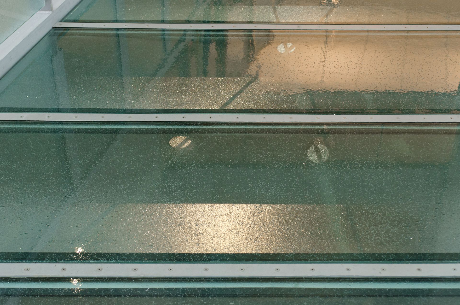 Glass-topped table with water droplets and reflections, seen through a window
