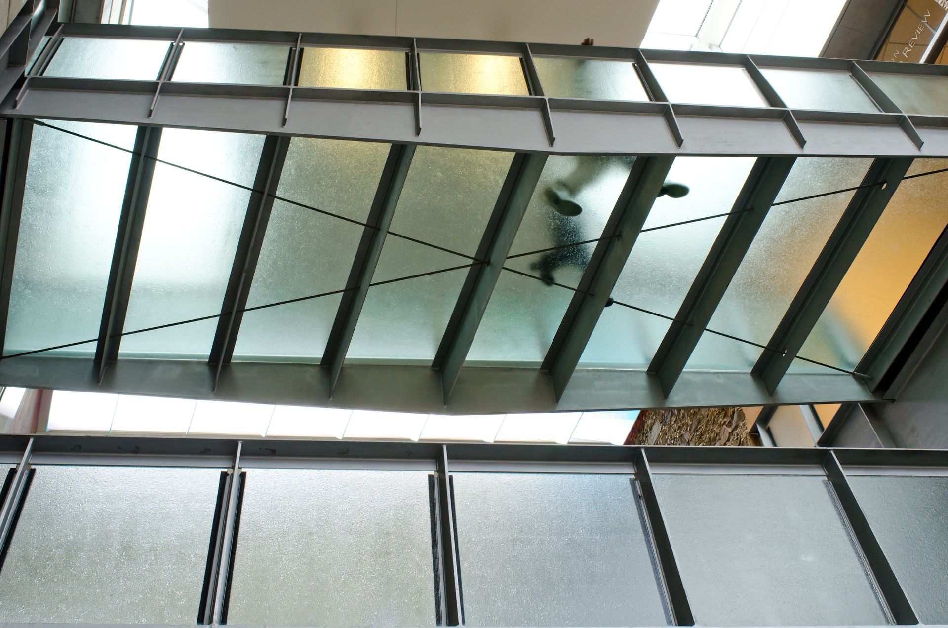 Glass canopy and skylights with metal beams reflecting light indoors
