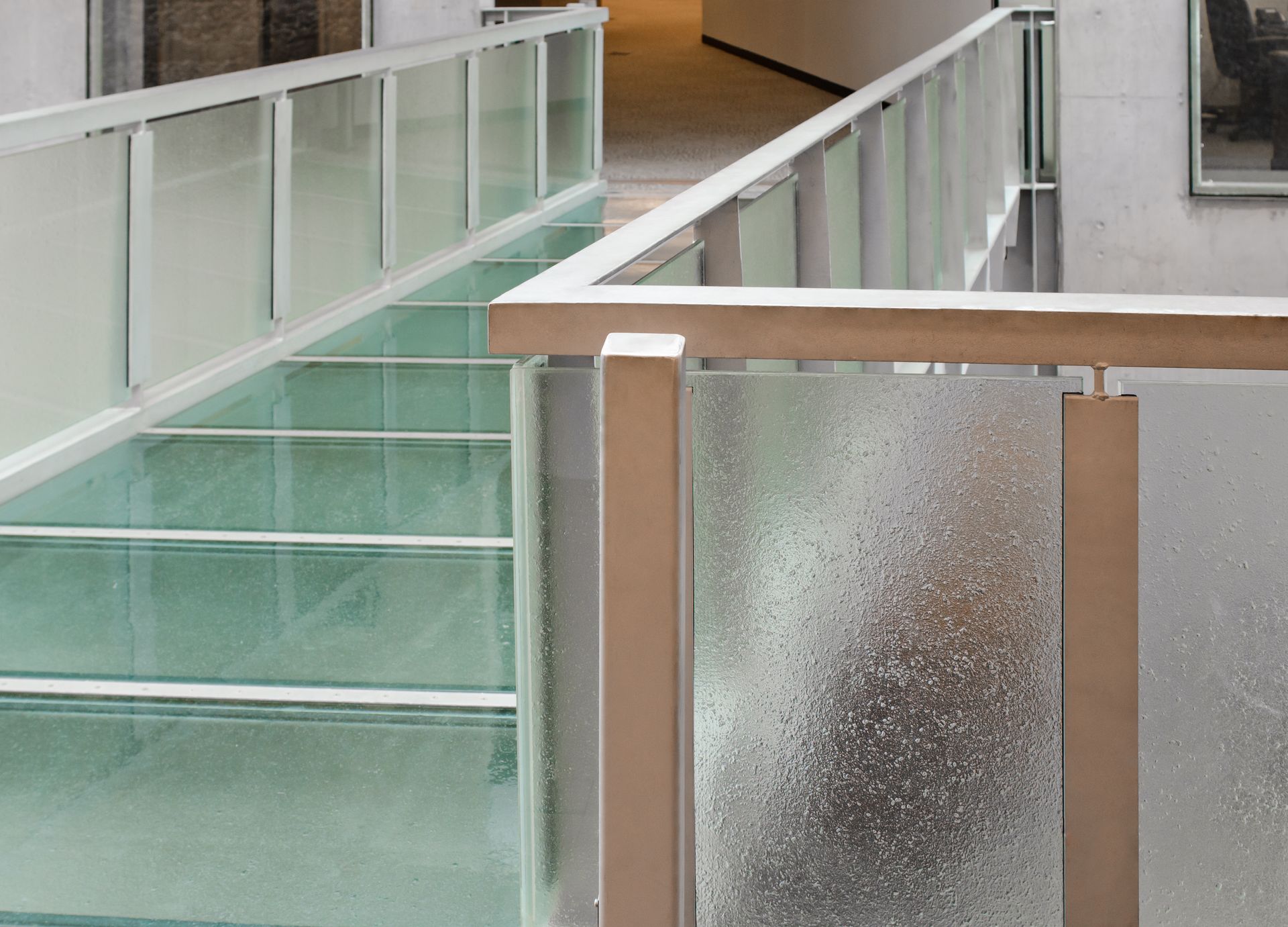 Modern indoor stairwell with glass railings and frosted glass panels