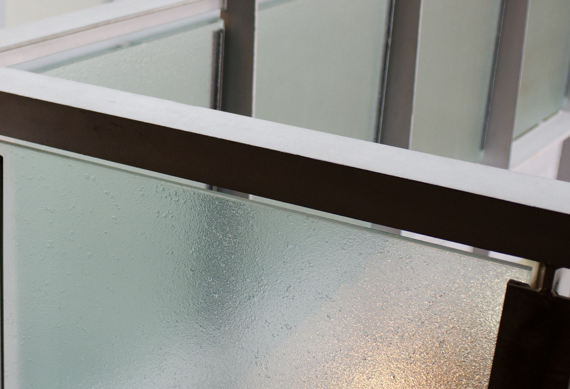 Frosted glass panels and dark wooden railing in a modern interior stairwell