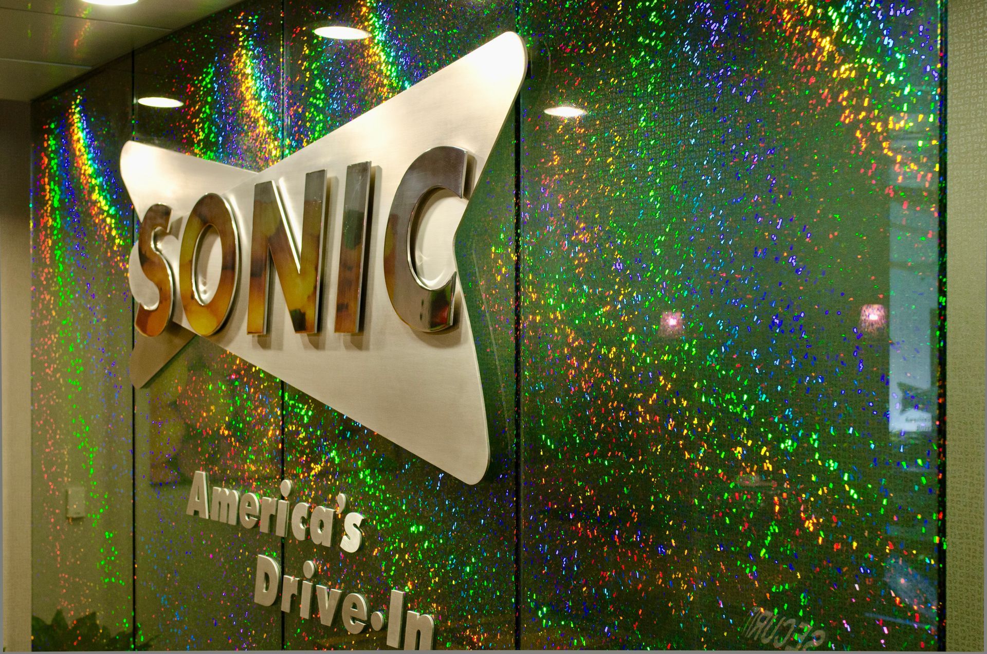 SONIC restaurant sign on a sparkling green wall with “America’s Drive-In” beneath it
