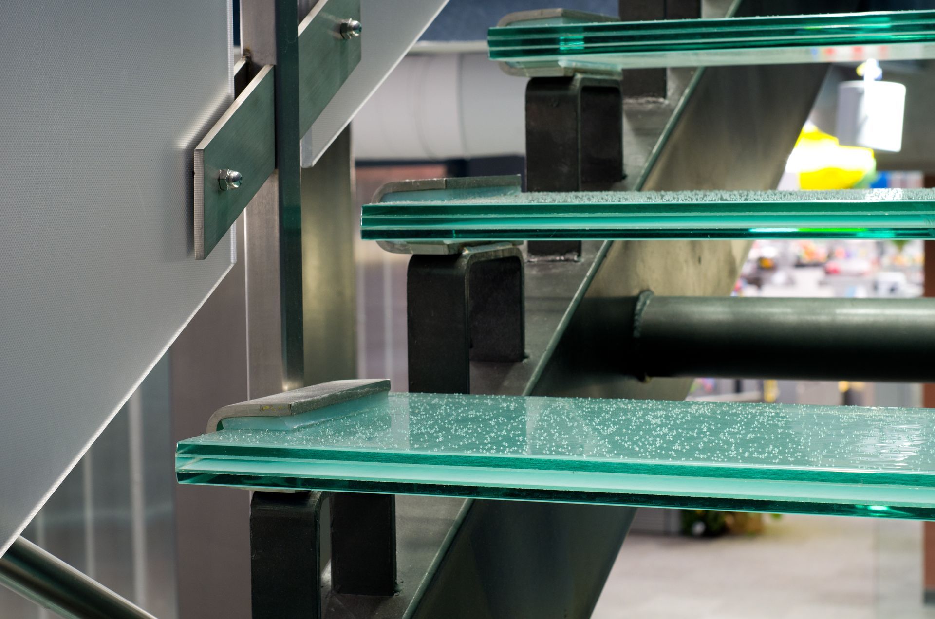 Green-tread staircase with black metal supports in an indoor setting