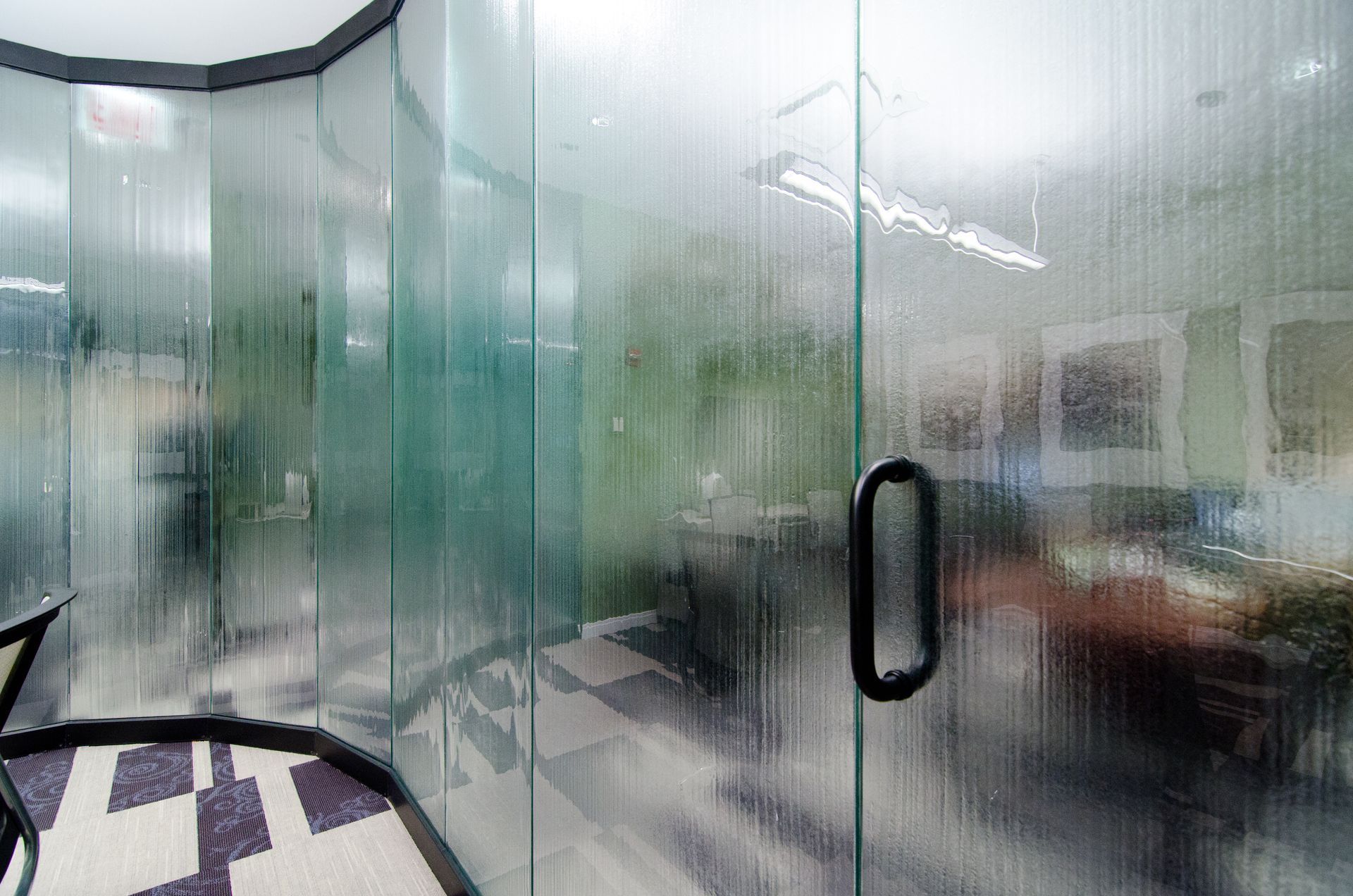 Blurred office interior with glass walls, a doorway handle, and chairs visible inside