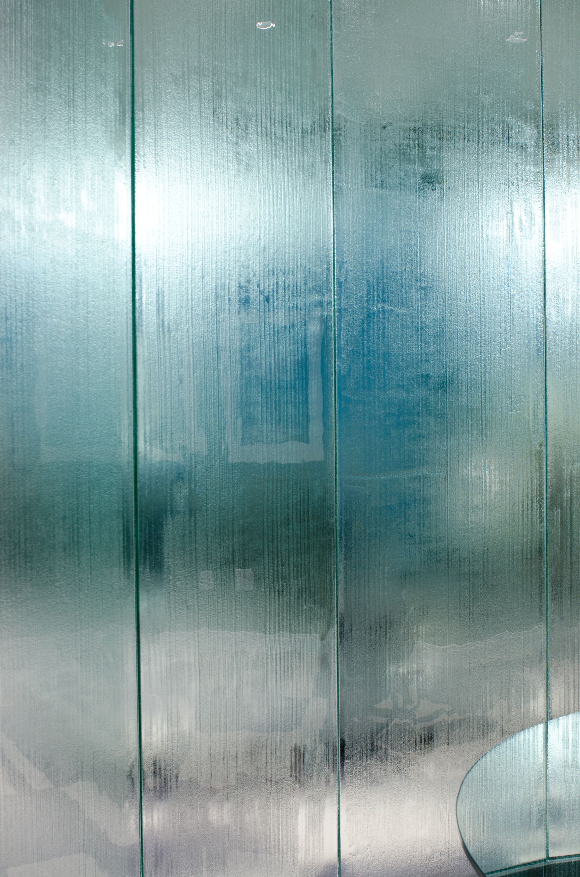 Blue-green metal wall with a vertical seam and a small white rounded object at bottom right