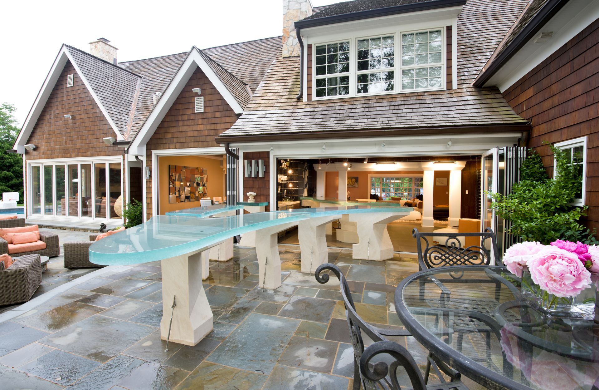 Backyard patio with turquoise water feature, stone floor, and house exterior with covered seating area