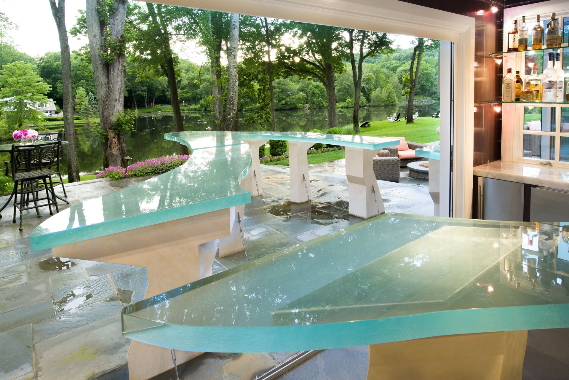 Modern glass-walled interior overlooking a turquoise pool and lush garden outside