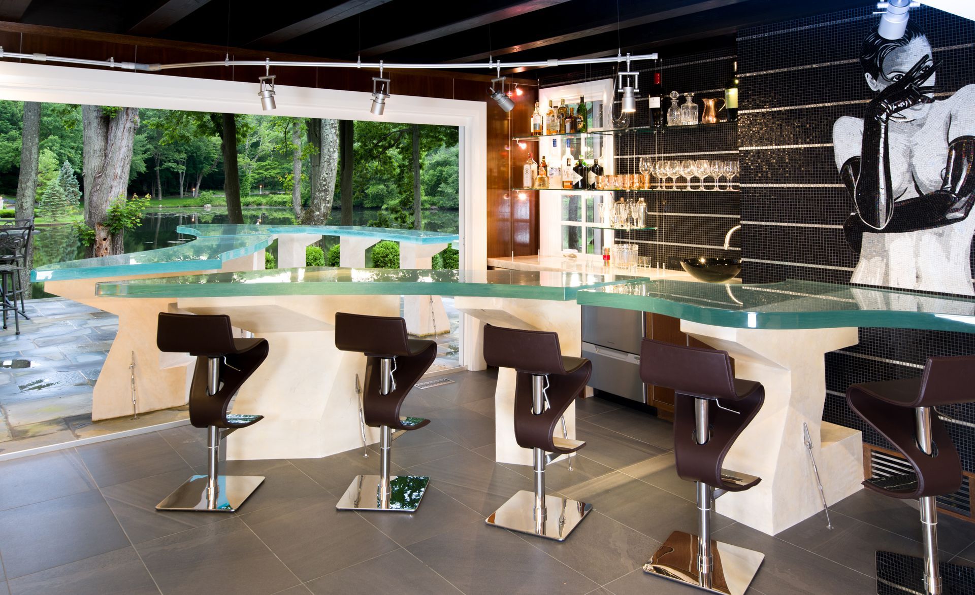 Modern bar with glossy black stools and a curved white counter, overlooking a lush green outdoor view