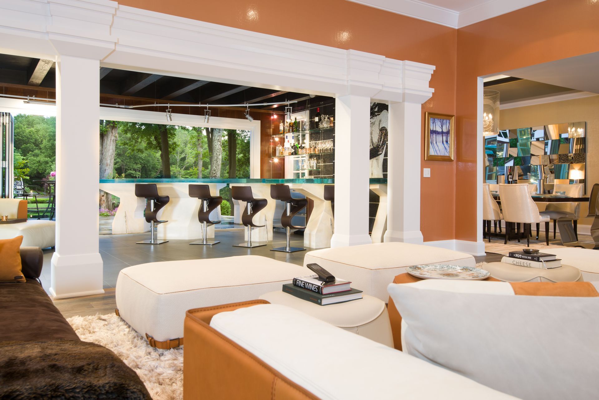 Modern living room with white sectional sofa, orange walls, and open bar seating overlooking a patio