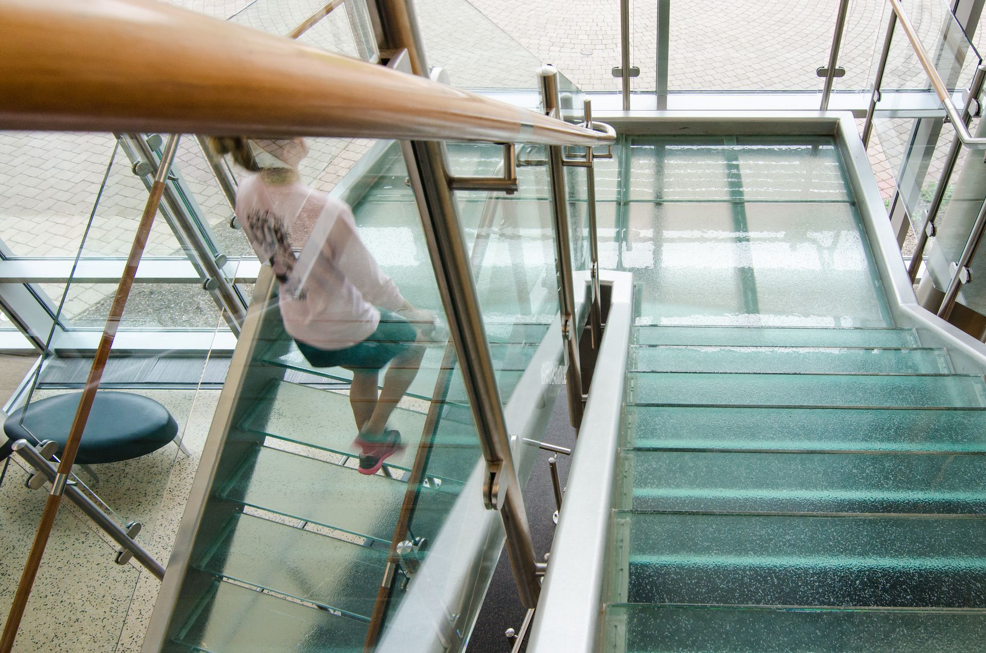 Person climbing glass-railed stairs in a modern building
