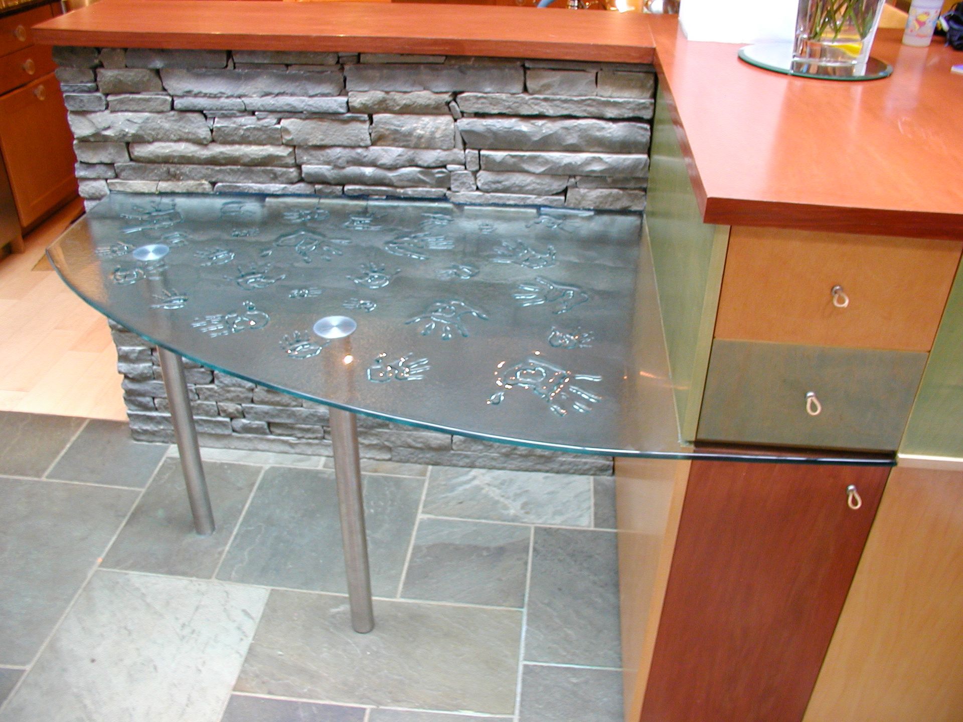 Bar with stone facade and custom glass tabletop with chrome legs.