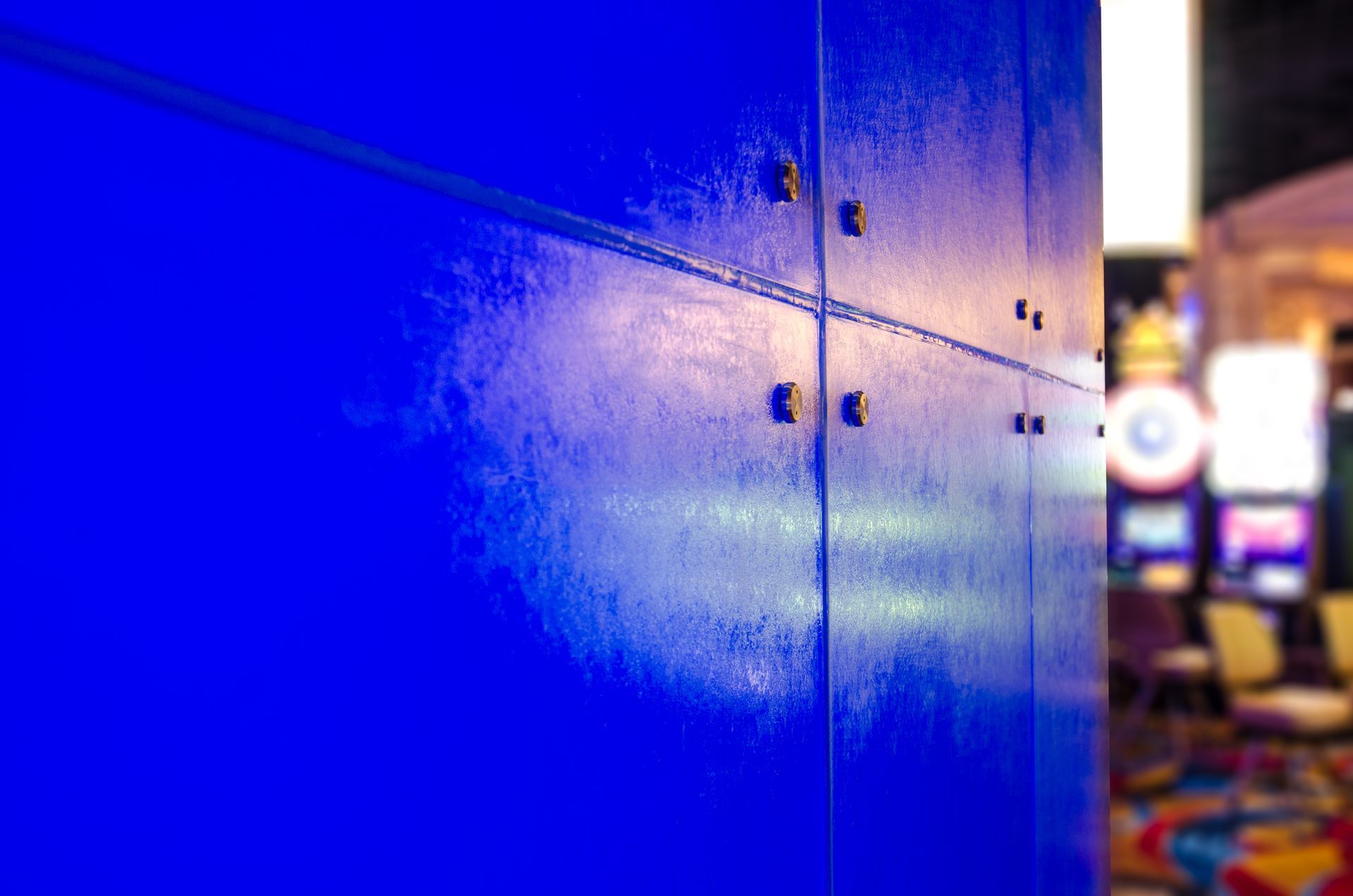 Close-up of a bright blue wall with blurred casino lights and machines in the background
