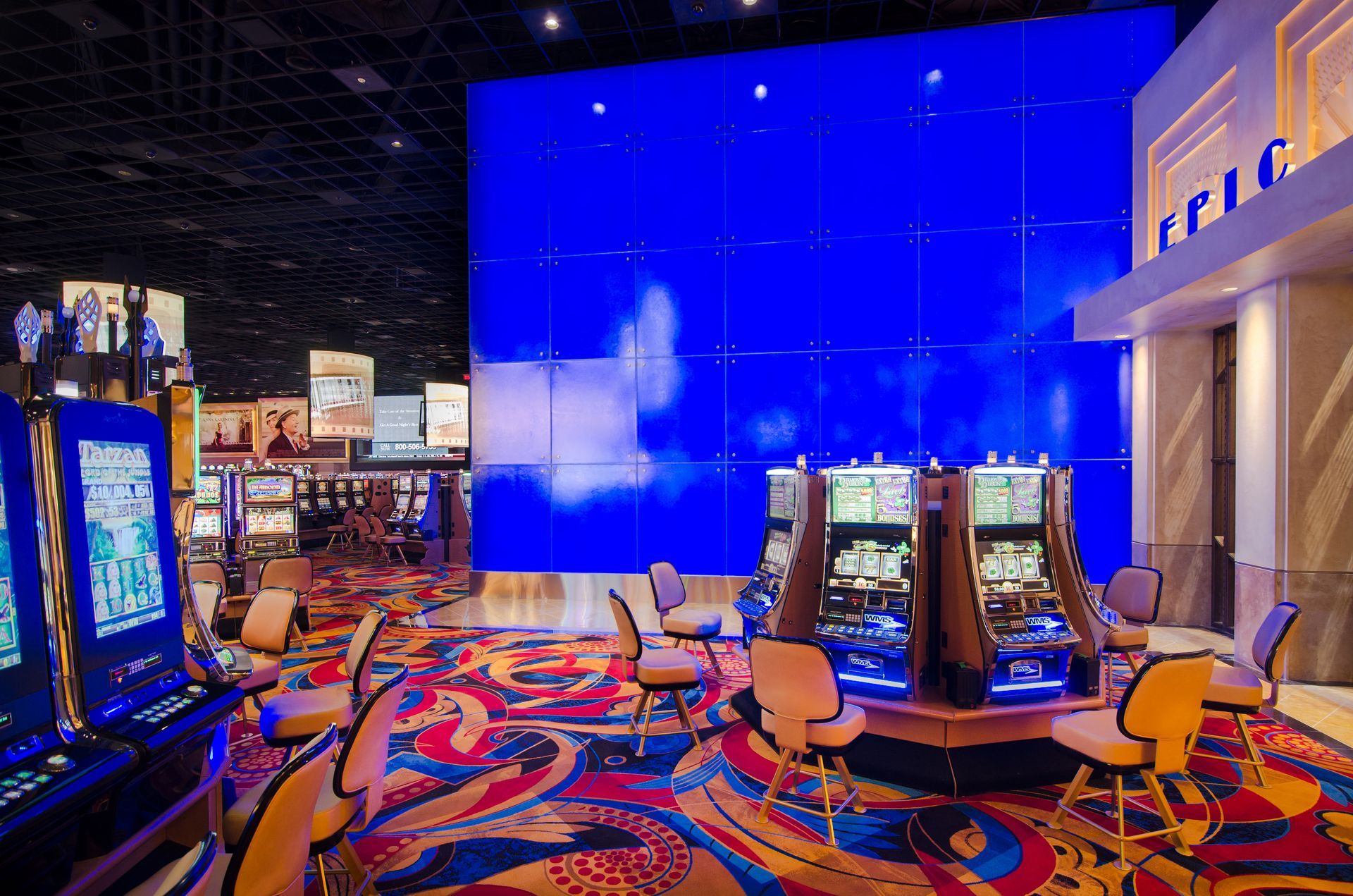 Bright casino floor with colorful slot machines and a large blue LED wall