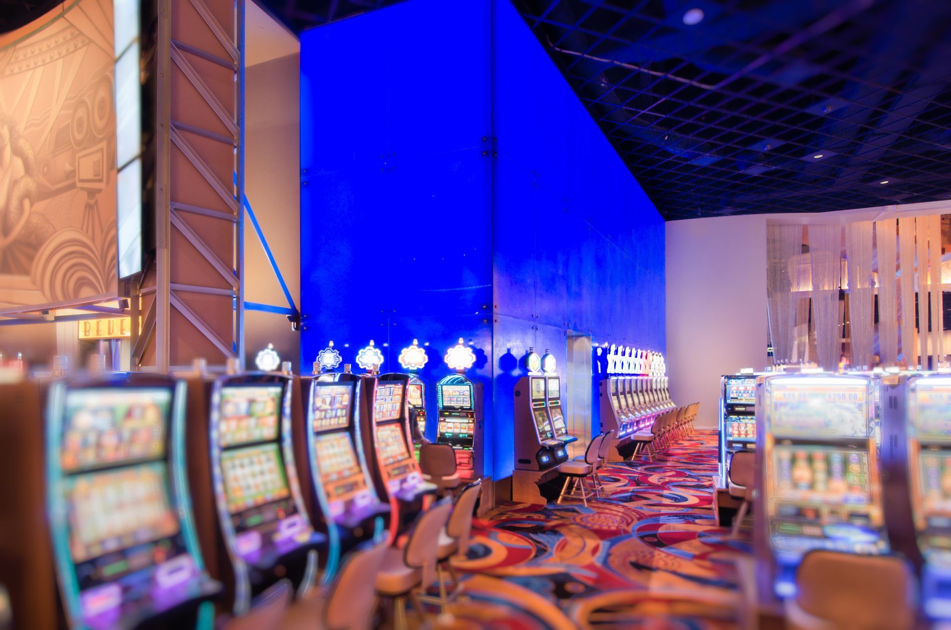 Colorful casino floor with rows of slot machines under blue lighting