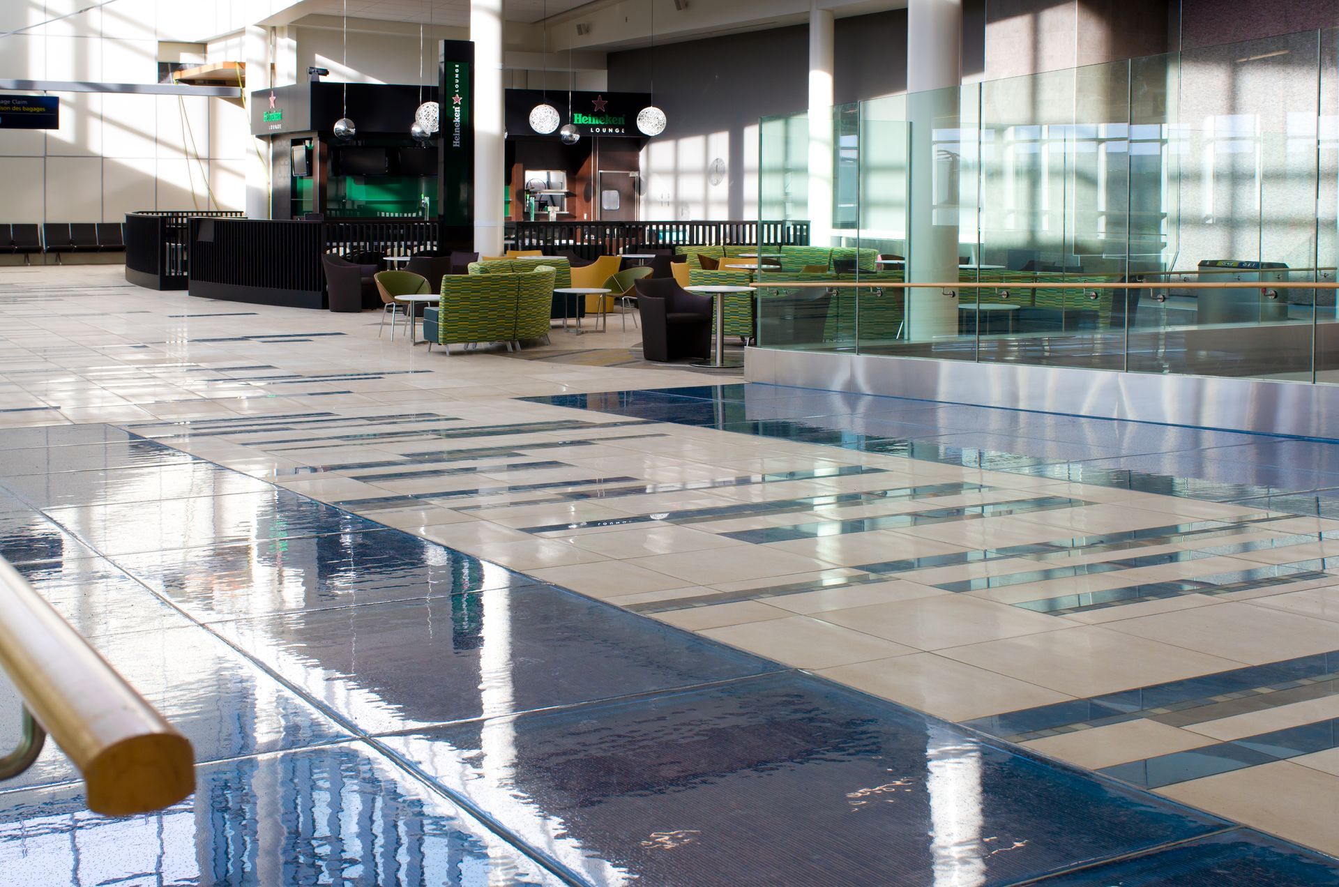 Empty airport terminal with wet tiled floor and seating near large windows