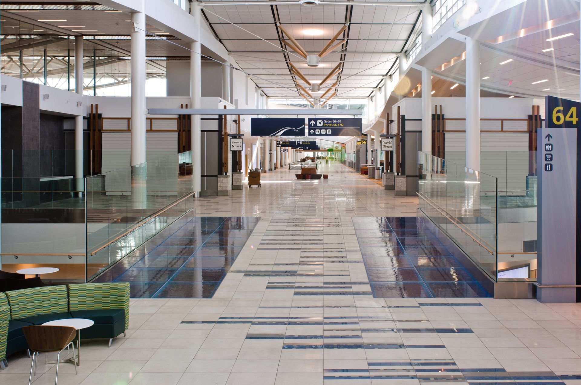 Empty airport terminal corridor with glass walls and gate signs