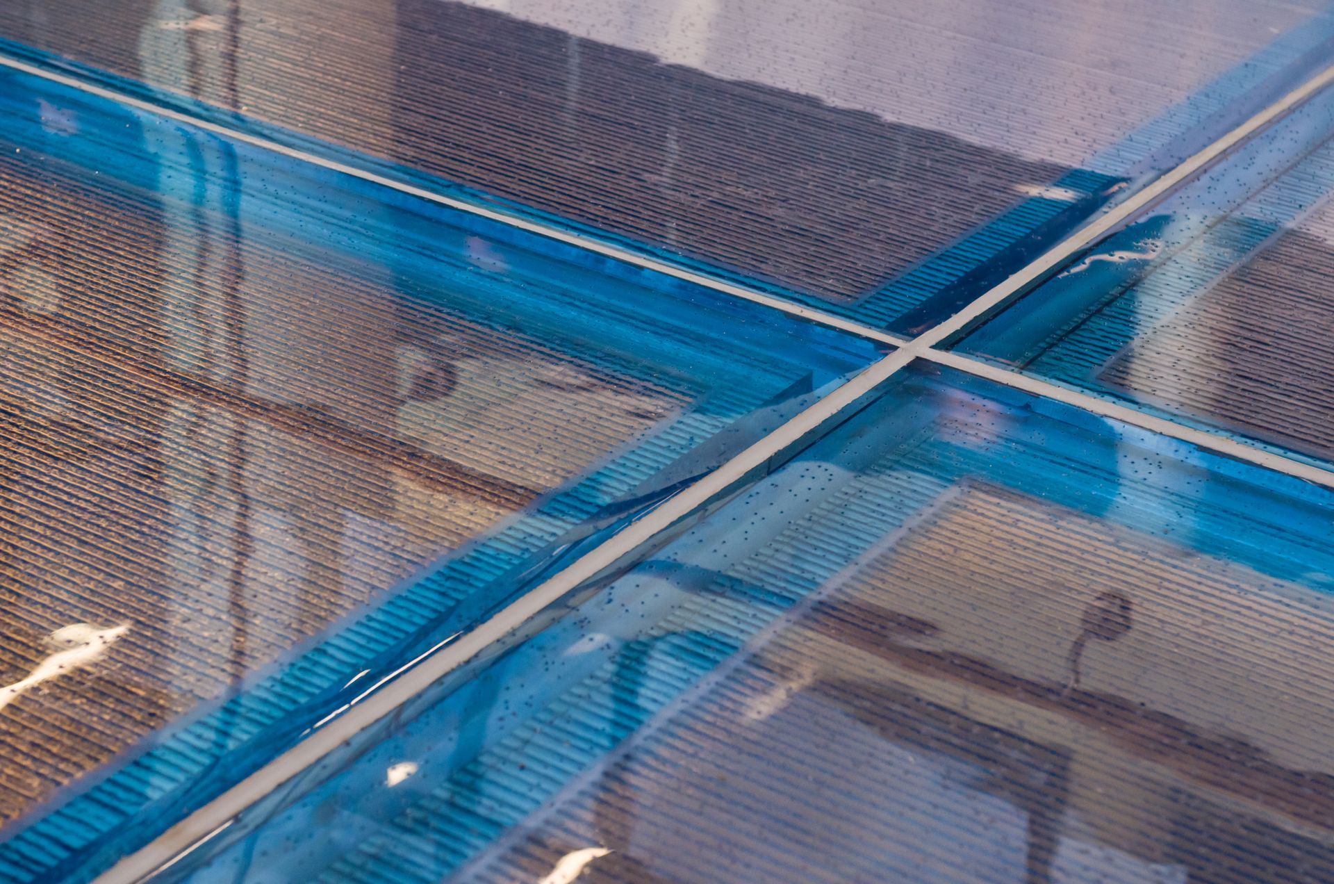 Blue mesh-covered pens with diagonal metal rods over a concrete surface