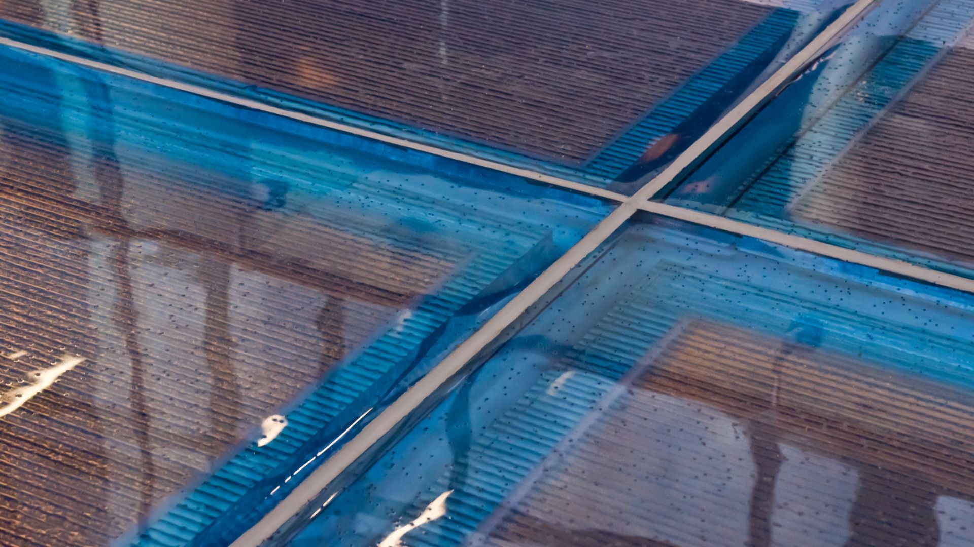 Blue tarps stretched over a metal frame, with reflections visible underneath