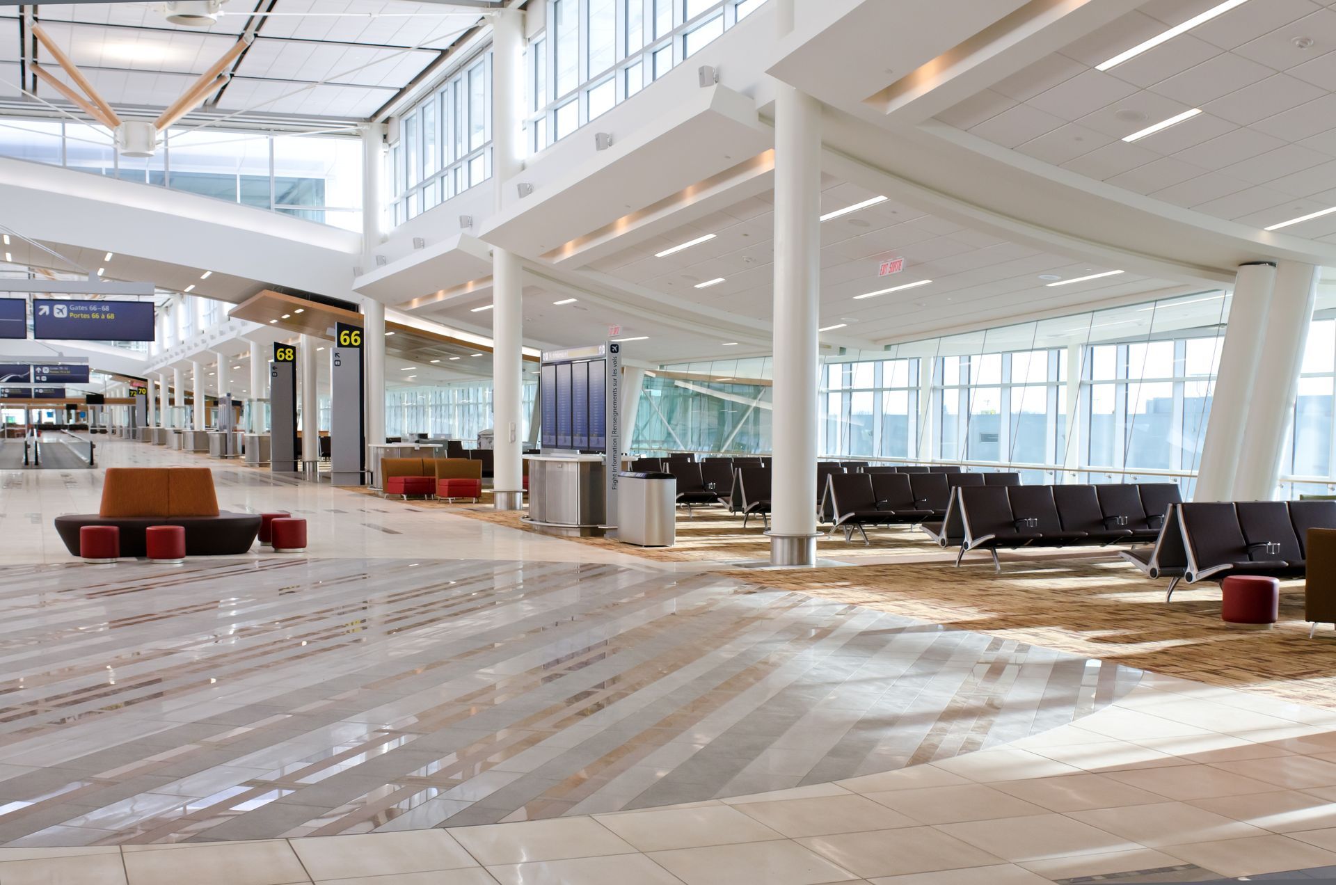 Empty modern airport terminal with bright windows, white columns, and construction materials on the floor