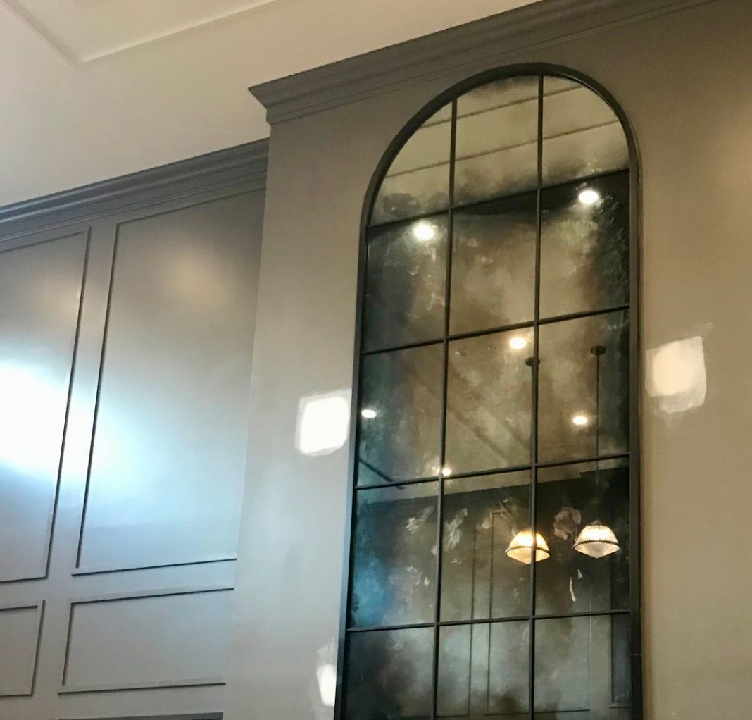 A large antique mirror is hanging on a wall in a room