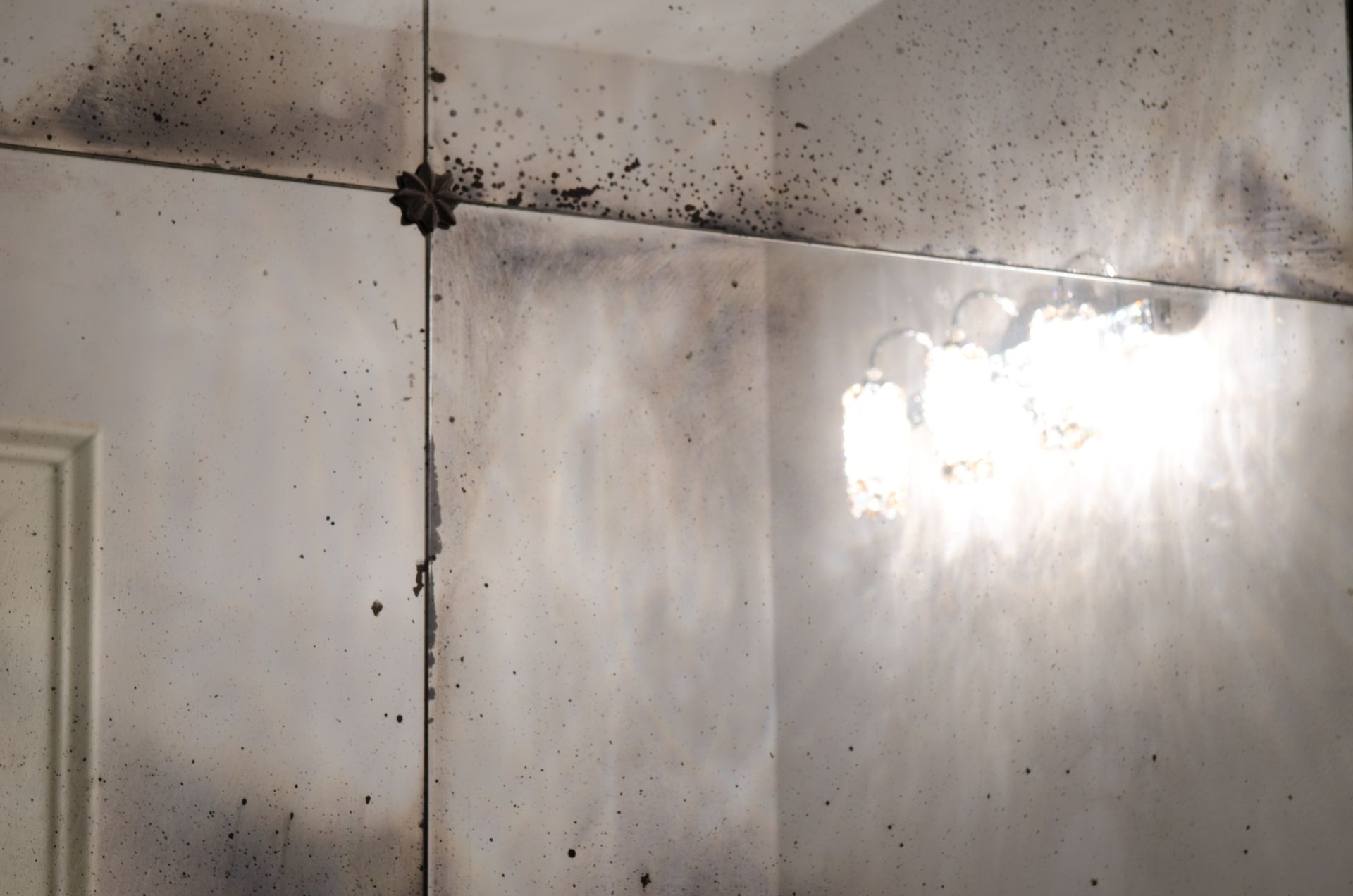 A room with an antique mirror and a light on the wall
