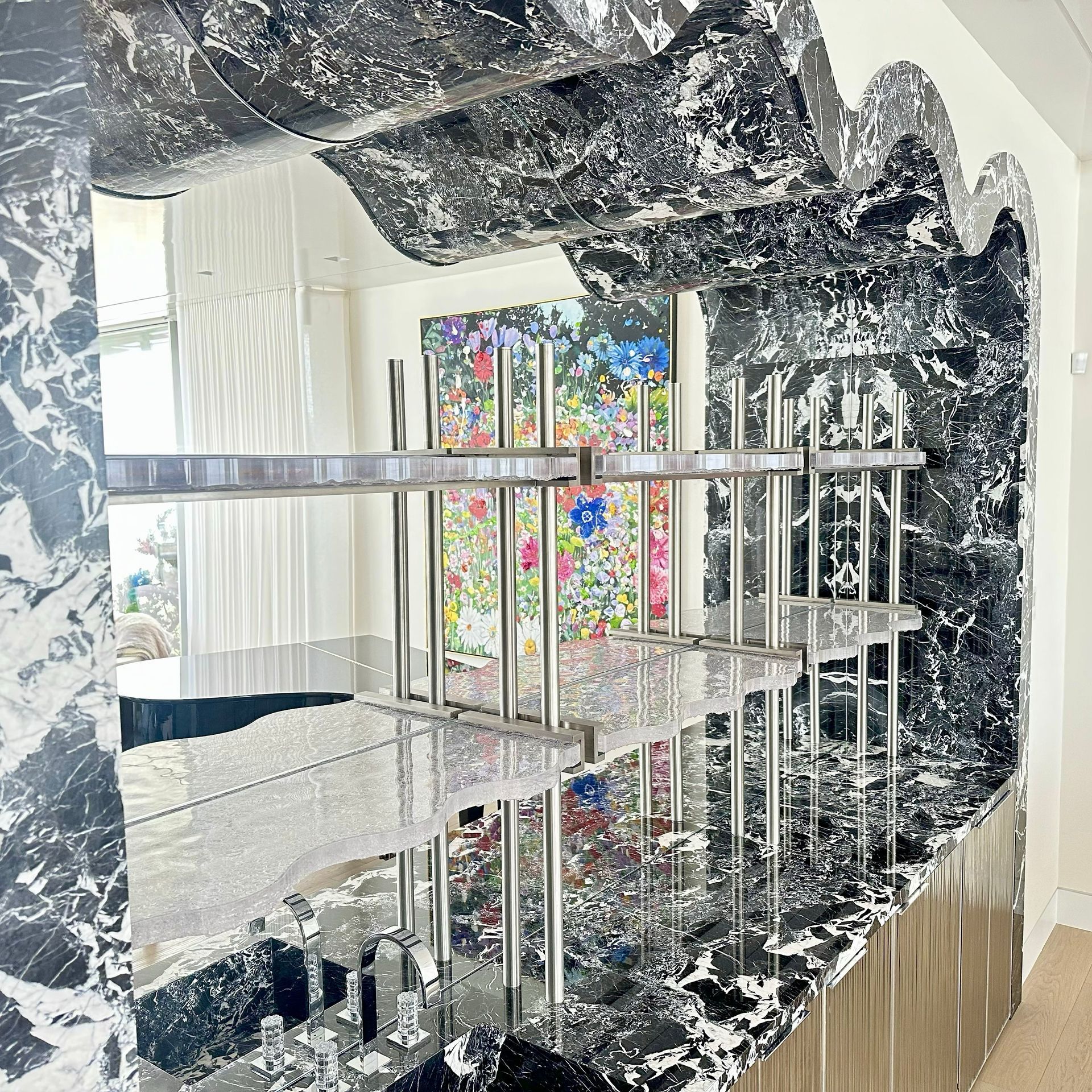 Mirrored abstract sculpture with chrome rails, reflecting a colorful window and black-and-white marbled surfaces