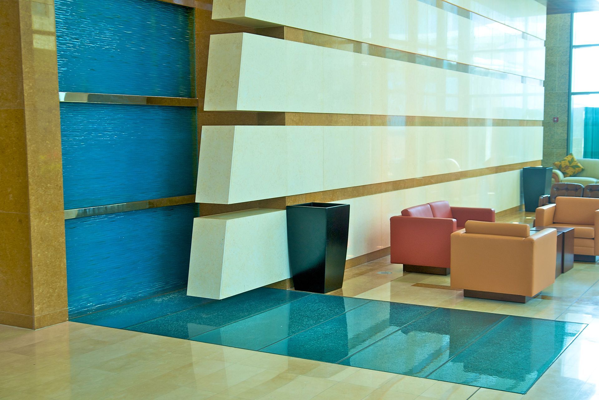 Modern lobby with blue wall, glass floor, and colorful lounge chairs nearby