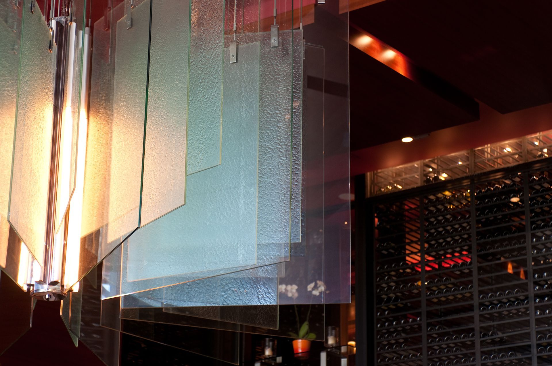 Abstract illuminated hanging panels in a dimly lit interior with warm orange and red lights.