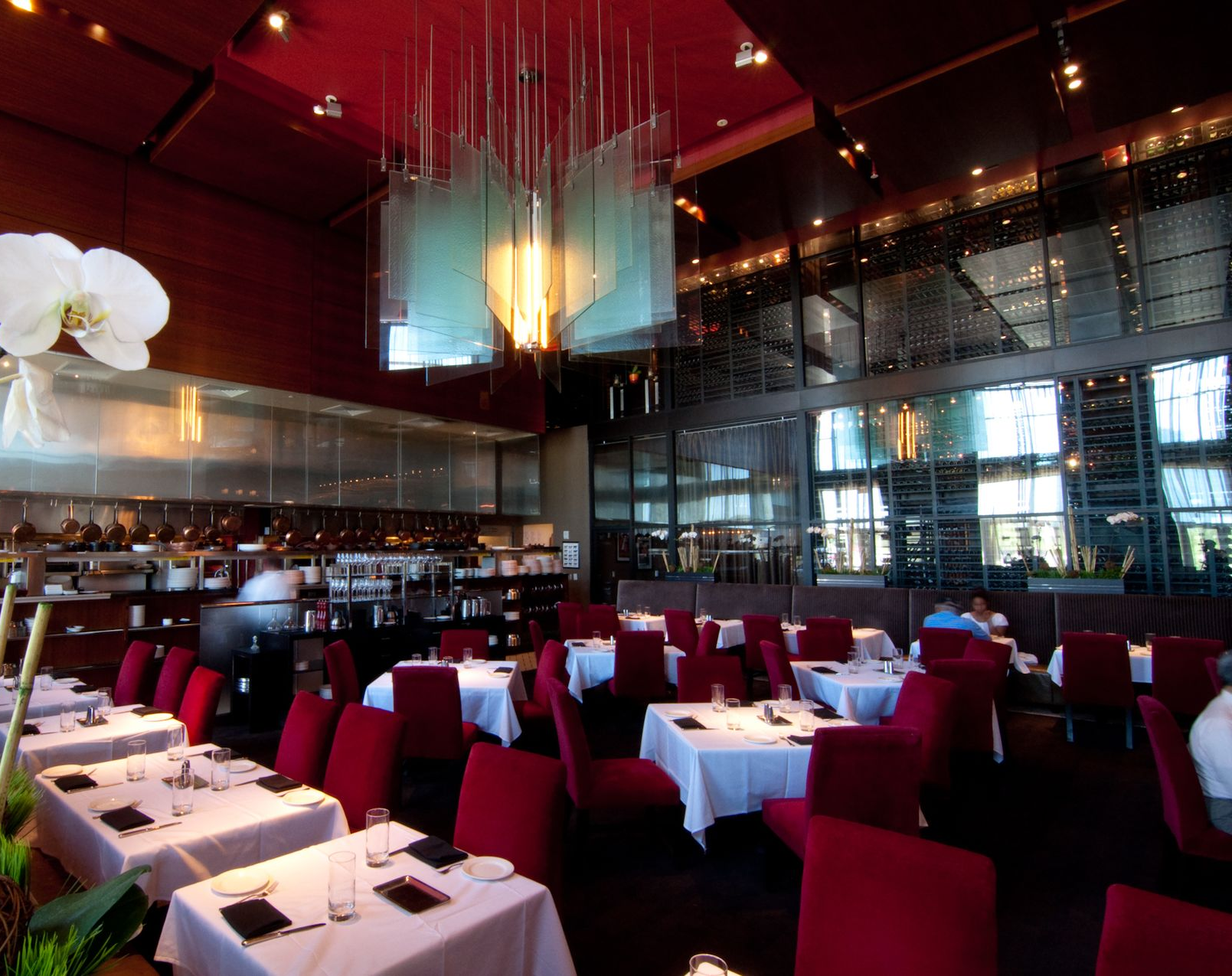 Elegant restaurant interior with red chairs, white tablecloths, and warm hanging lights
