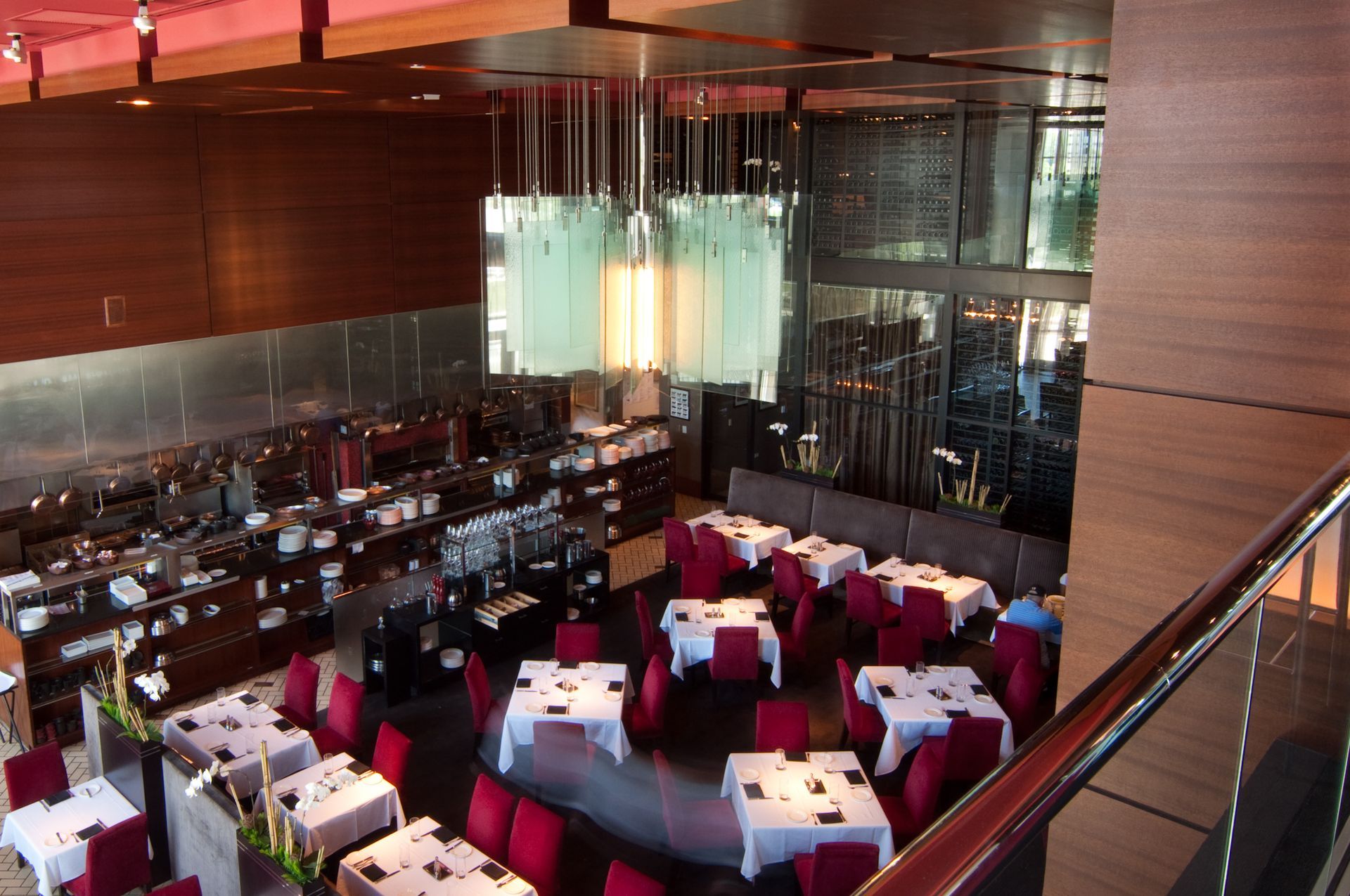 Upscale restaurant interior with red chairs, white tablecloths, and a large glass chandelier