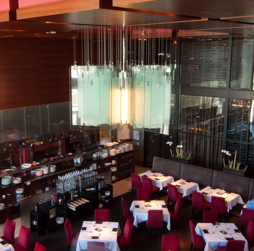 Modern hotel restaurant with red chairs, white tablecloths, and a hanging glass chandelier