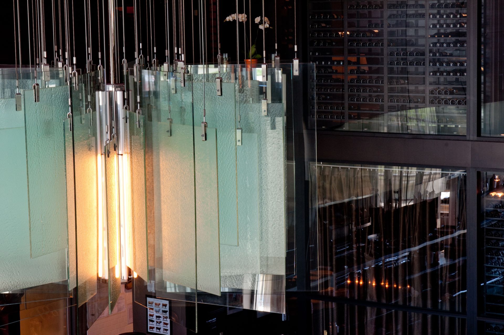 Modern glass building interior with hanging lights and a glowing vertical light panel