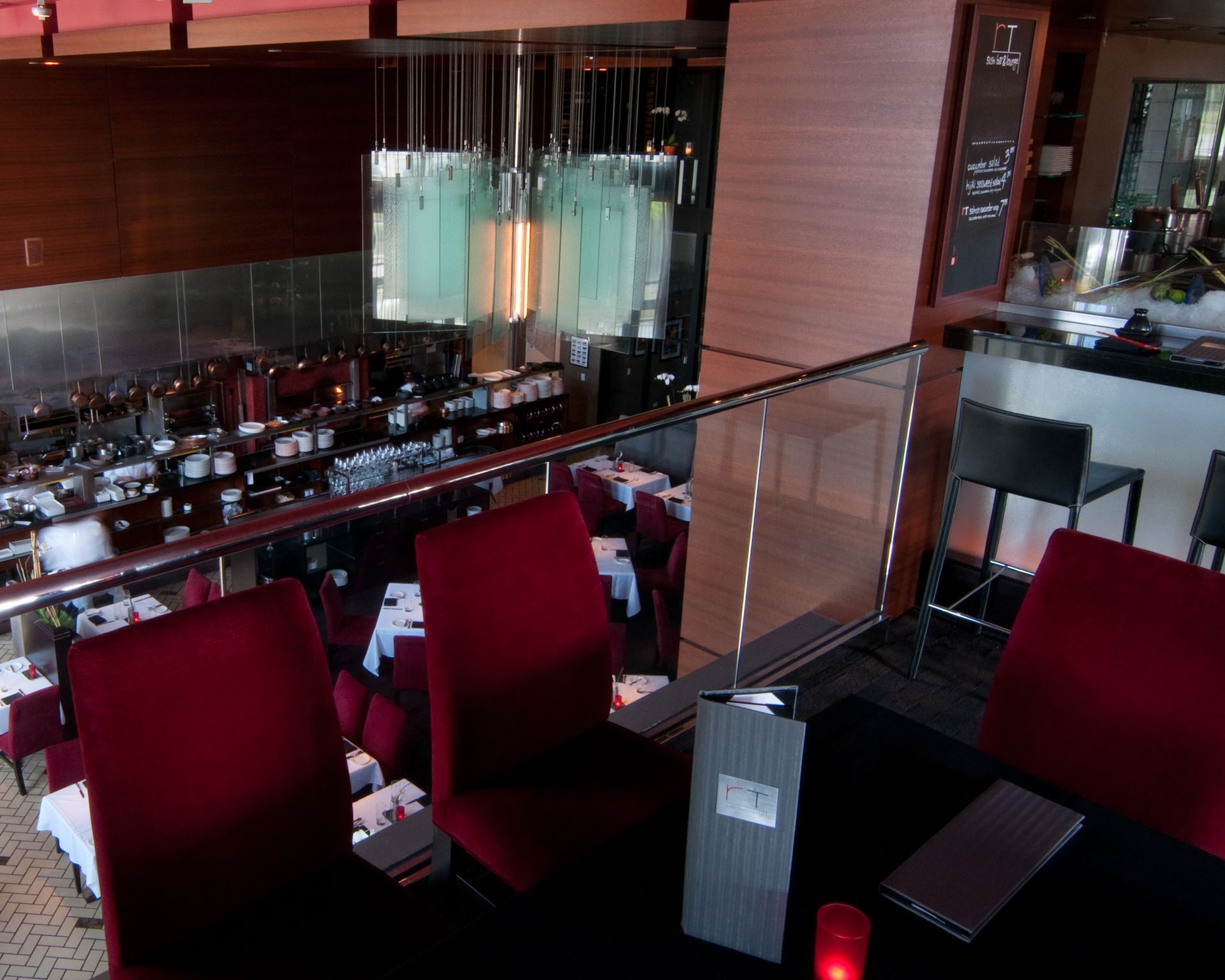 Modern restaurant interior with red chairs, glass railing, and bar seating