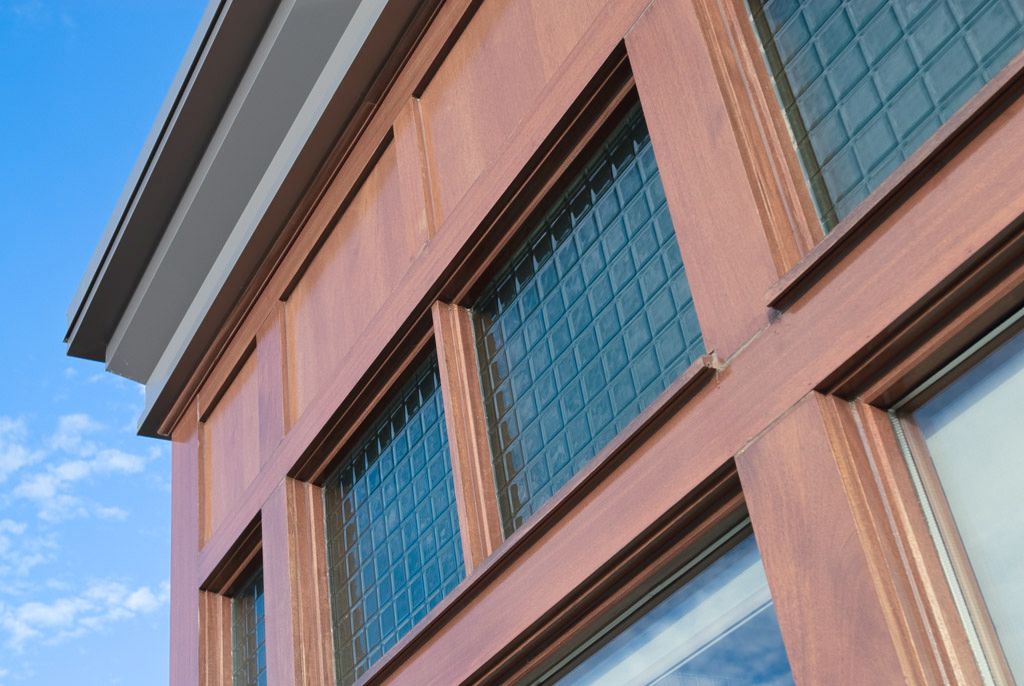 Wooden building facade with textured grid windows against a blue sky.