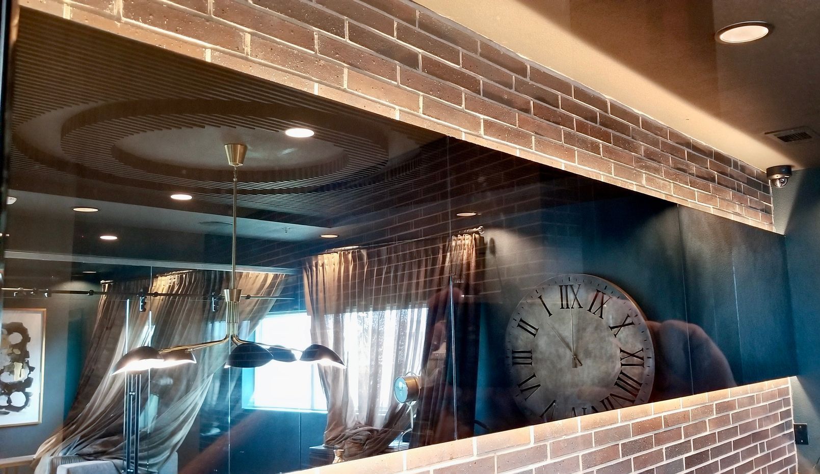 A mirror with a clock on it and a brick wall behind it