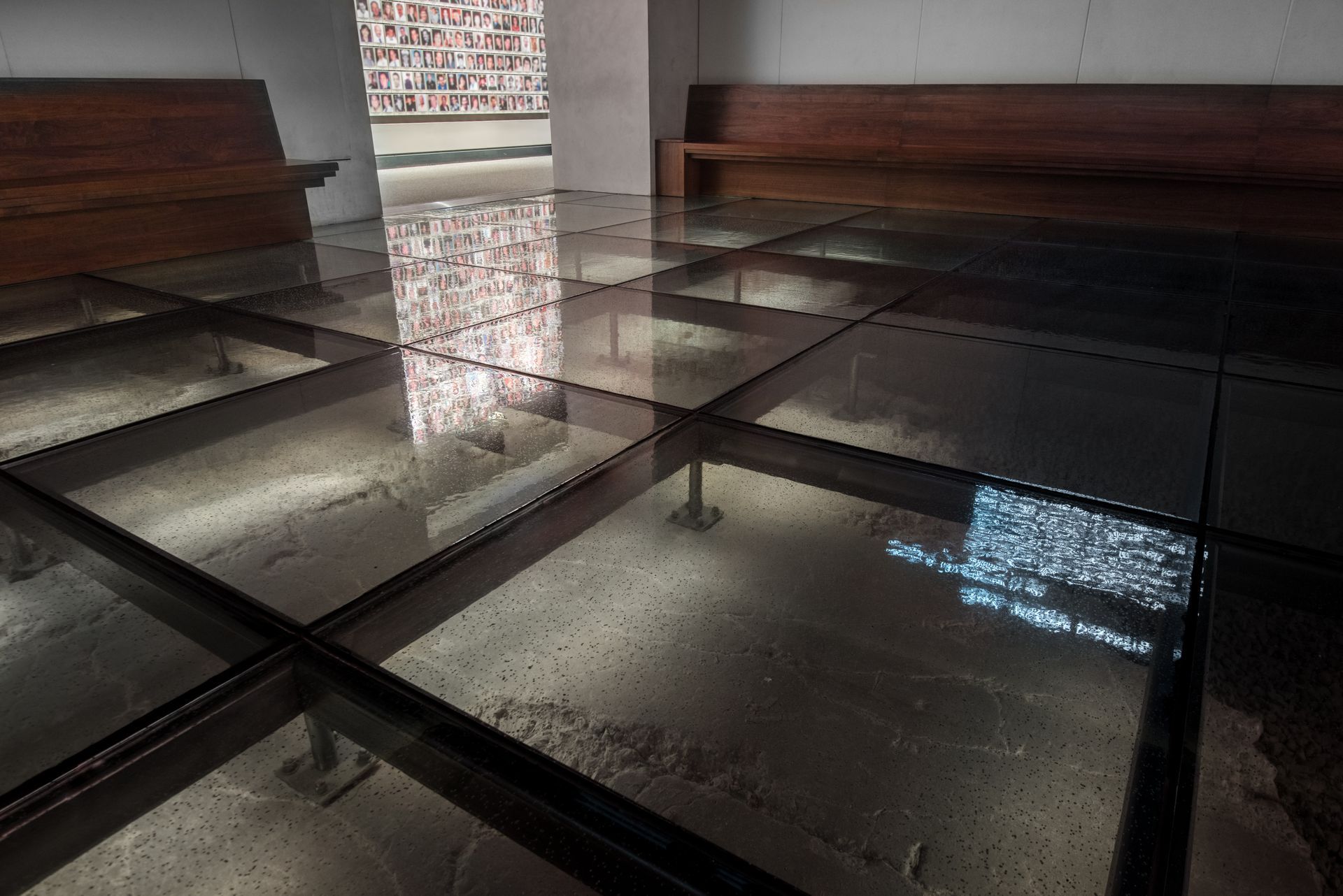 Shiny black tiled floor with wooden benches and a bright doorway in the background