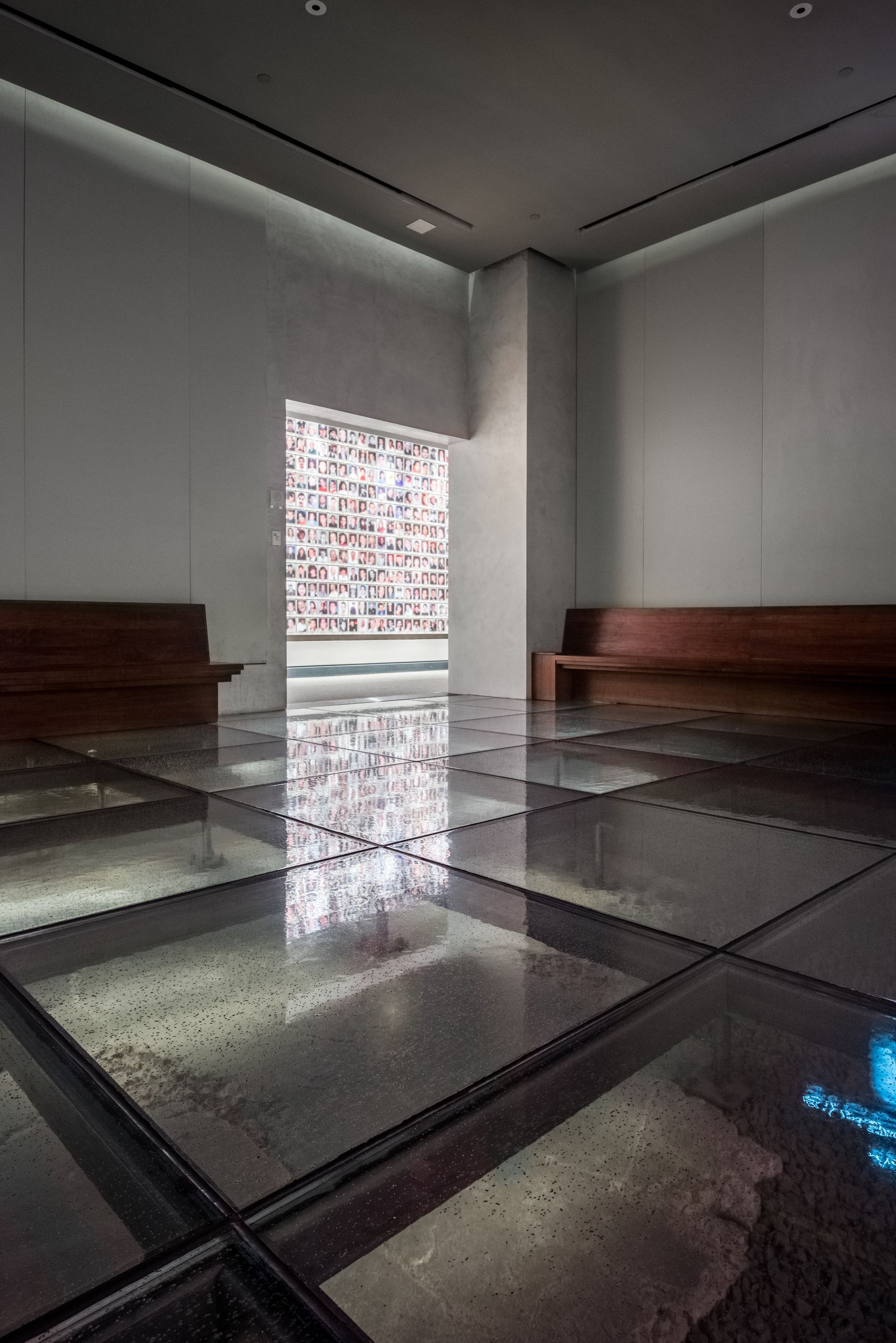Empty modern room with polished reflective floor, benches, and a bright window view in the center.
