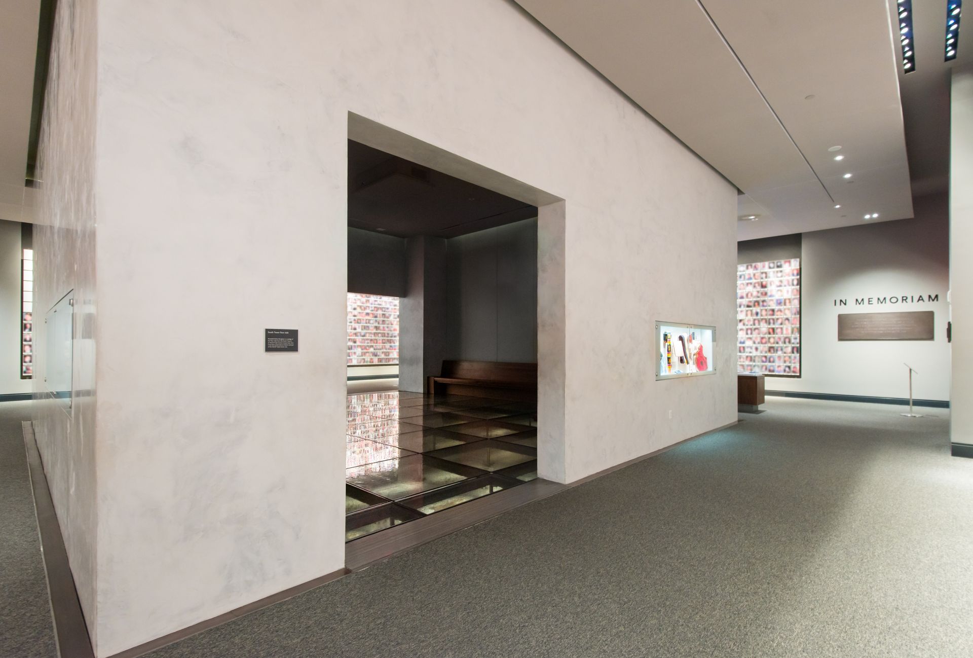 Modern gallery hallway with gray walls, recessed lights, and a stair opening in the center