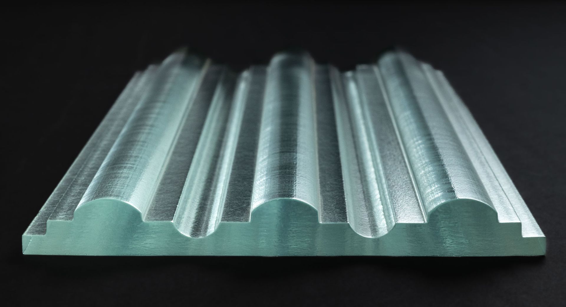 A close up of a piece of cast glass on a black background.