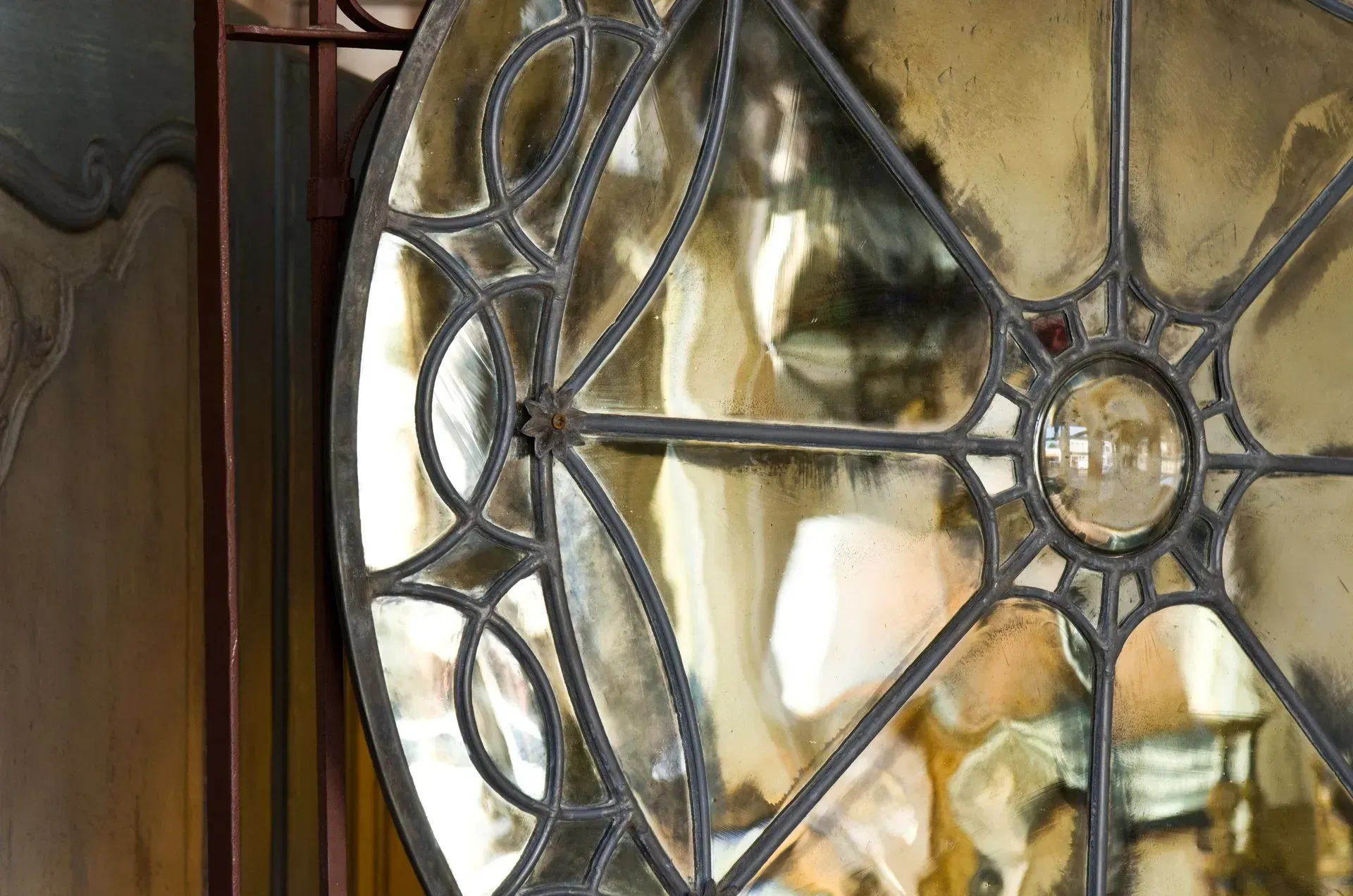Close-up of a circular window with decorative leaded glass patterns framed in dark metal.
