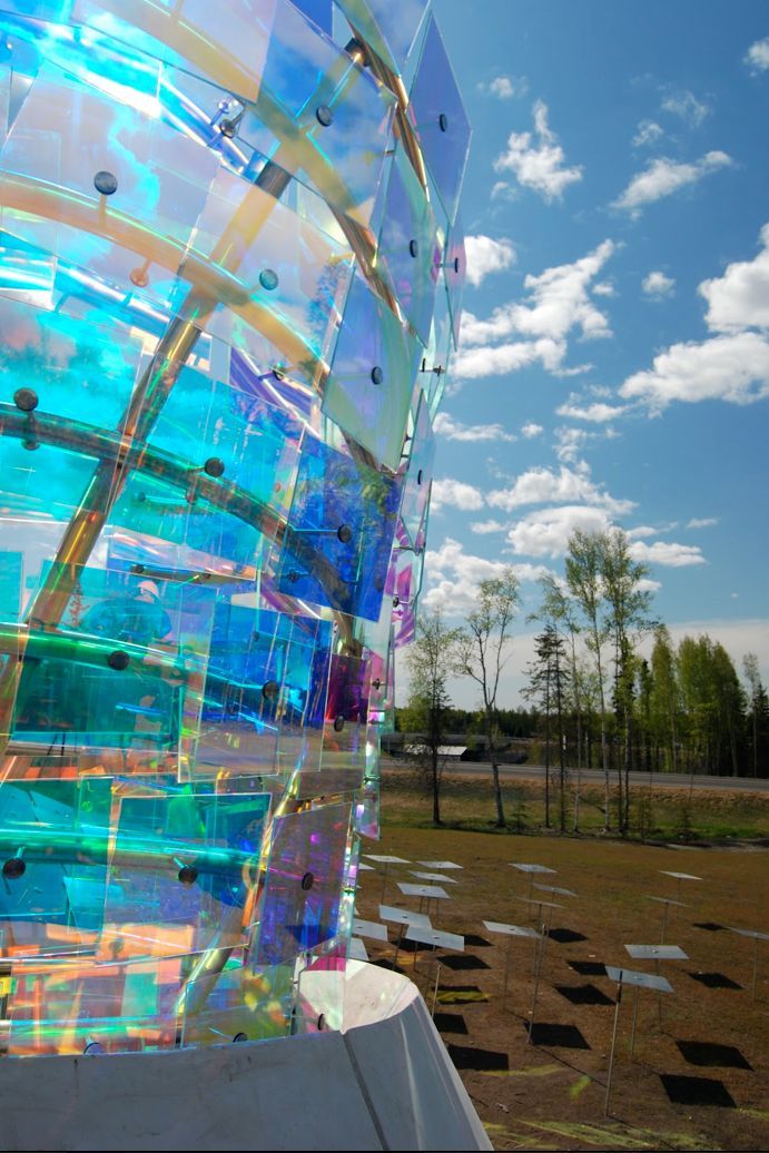 Close-up of a colorful iridescent glass sculpture against a blue sky in a park