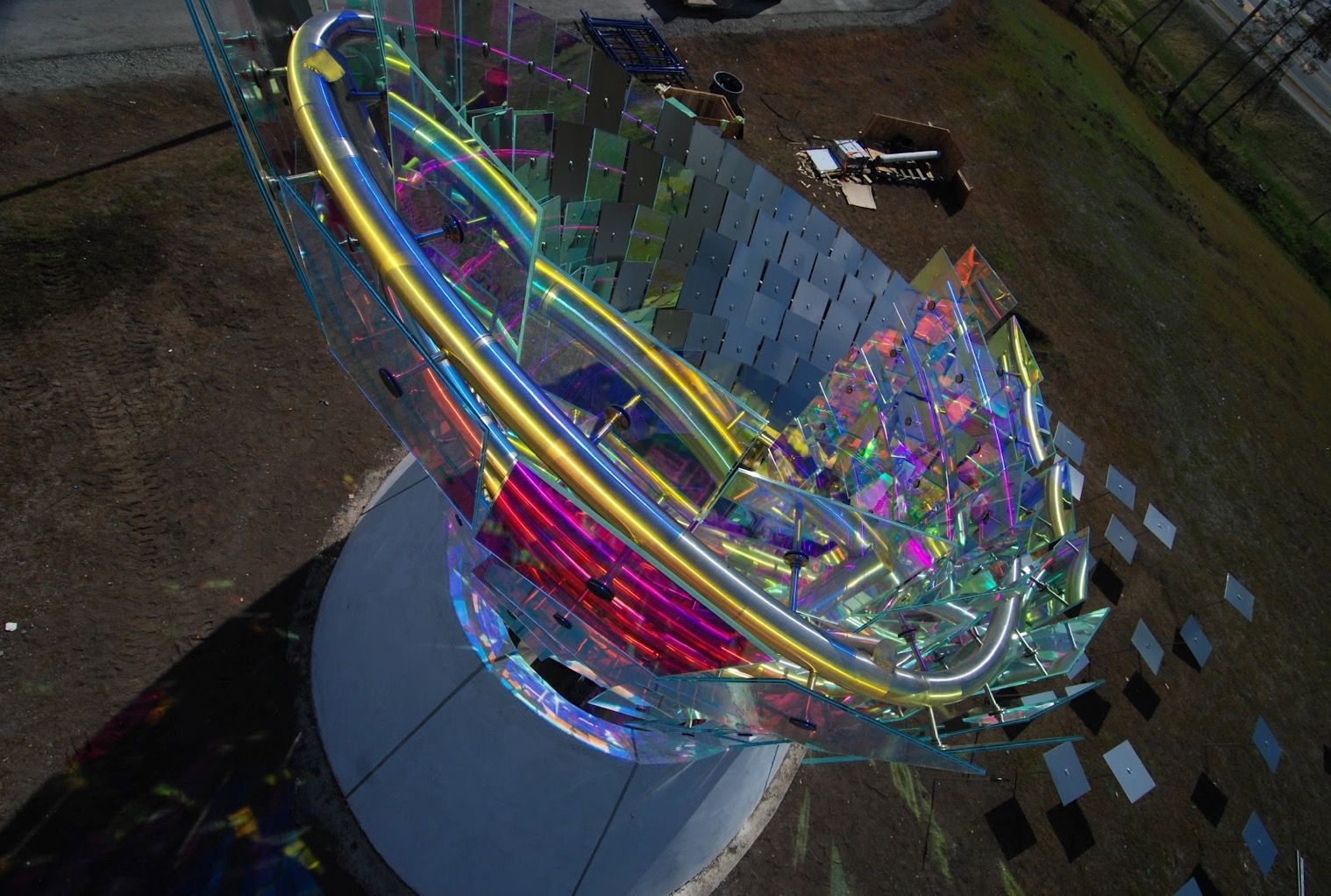 Colorful abstract neon ring sculpture on a pedestal in a dark outdoor setting