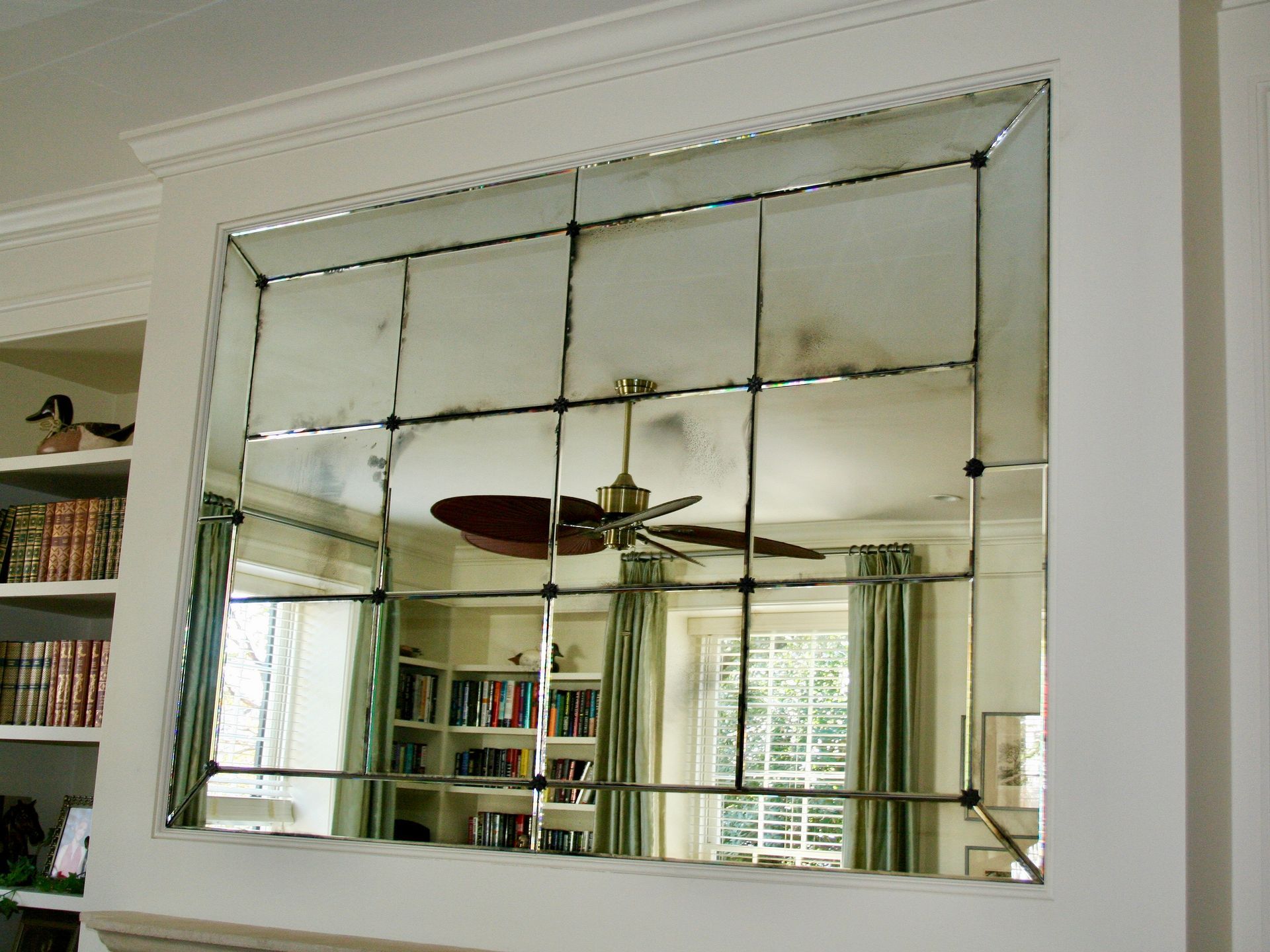 A ceiling fan is reflected in a large mirror in a living room