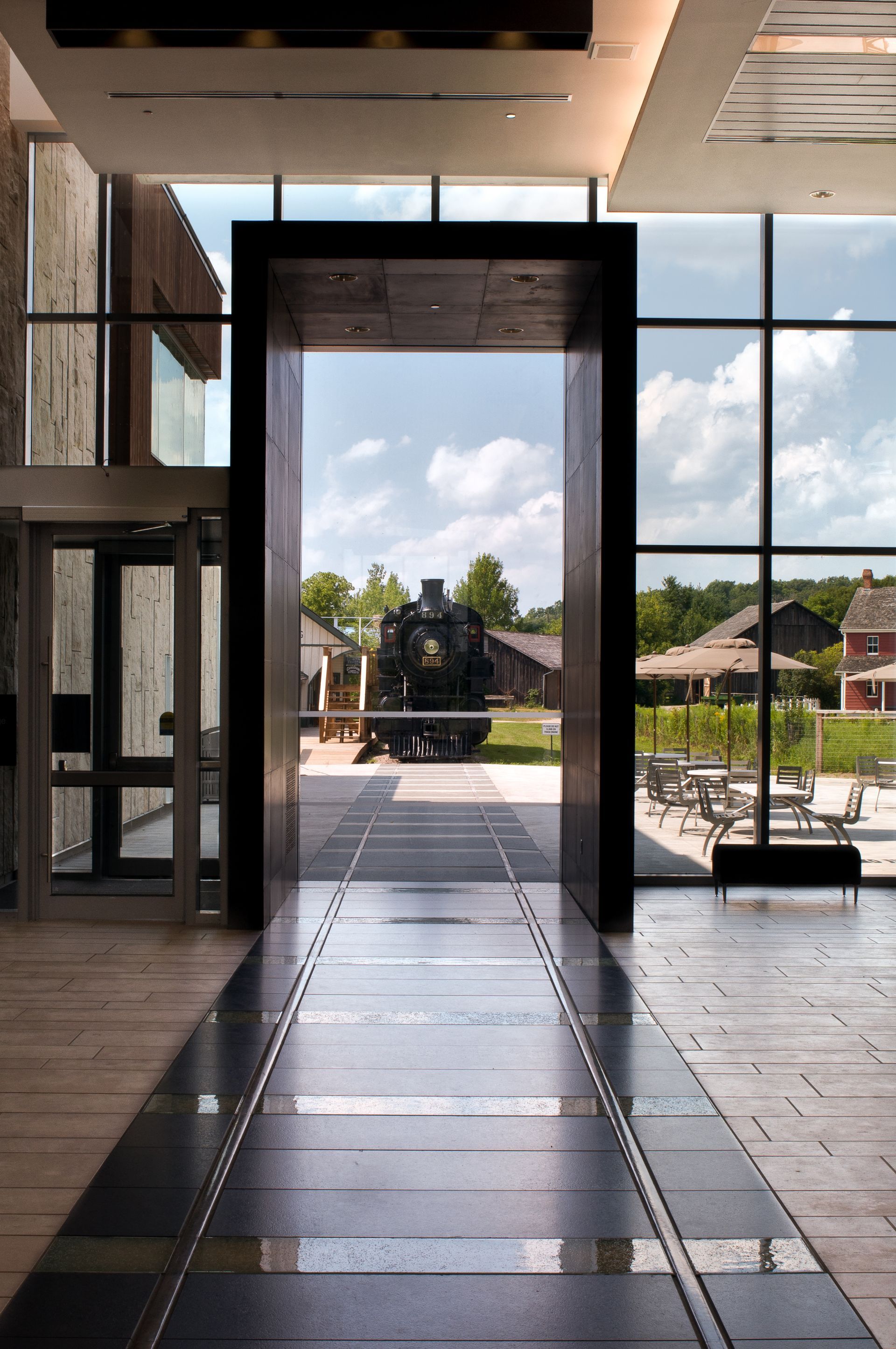 Modern lobby with glass doors opening to a statue and courtyard beyond