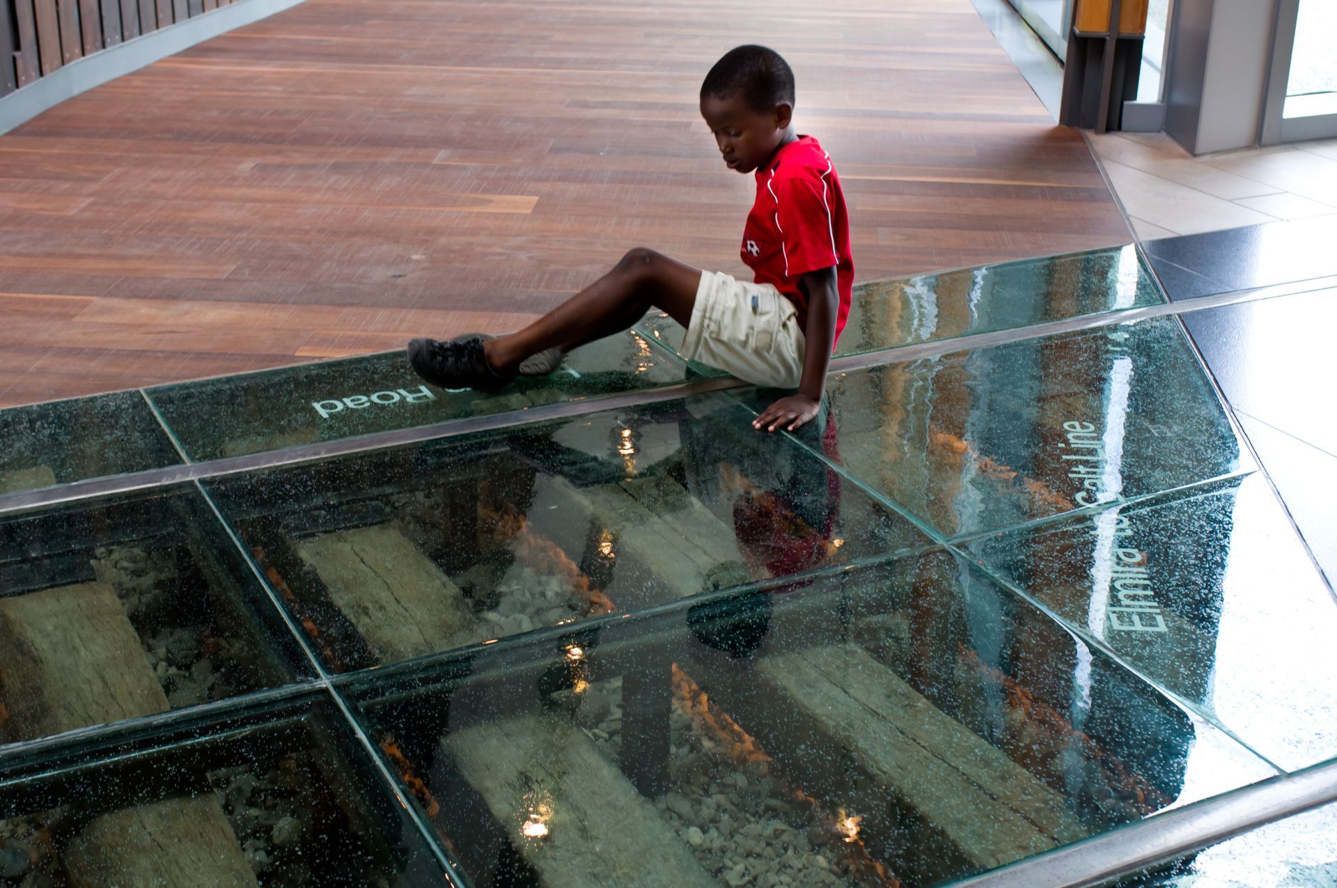 Child sitting on a glass floor over a display of building interiors
