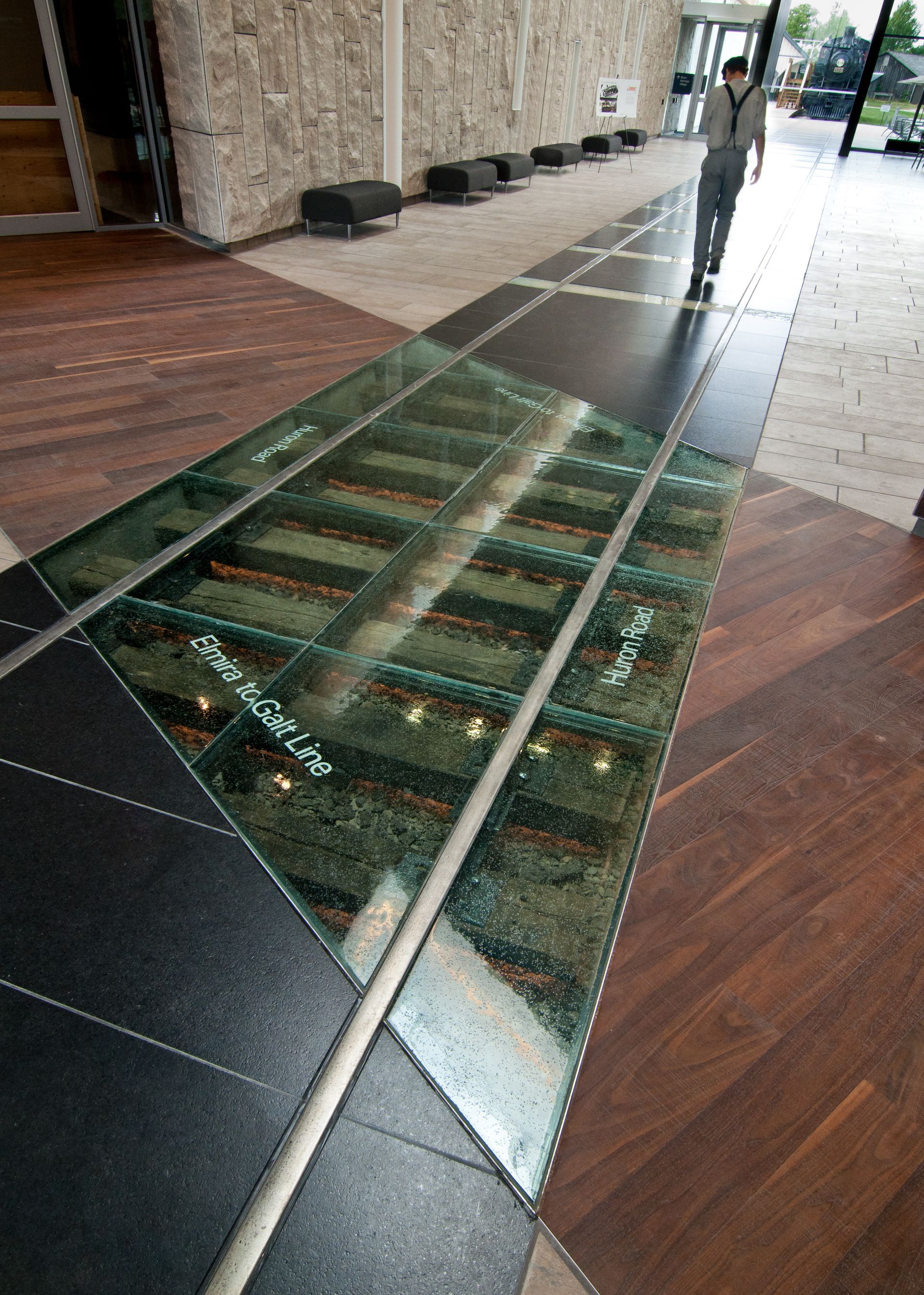 Glass floor panel over a shallow decorative channel in a modern building lobby
