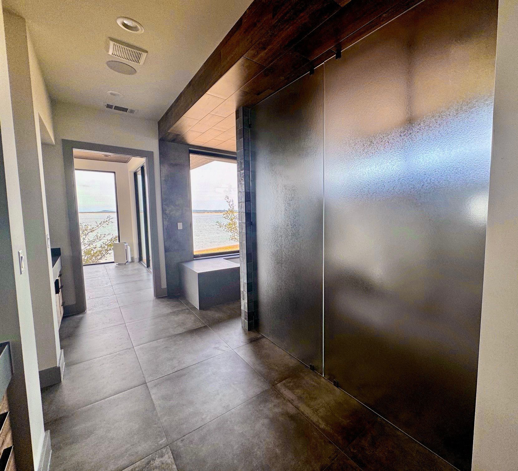 Hallway with large metal sliding door, tile floor, and view of outdoor seating area.