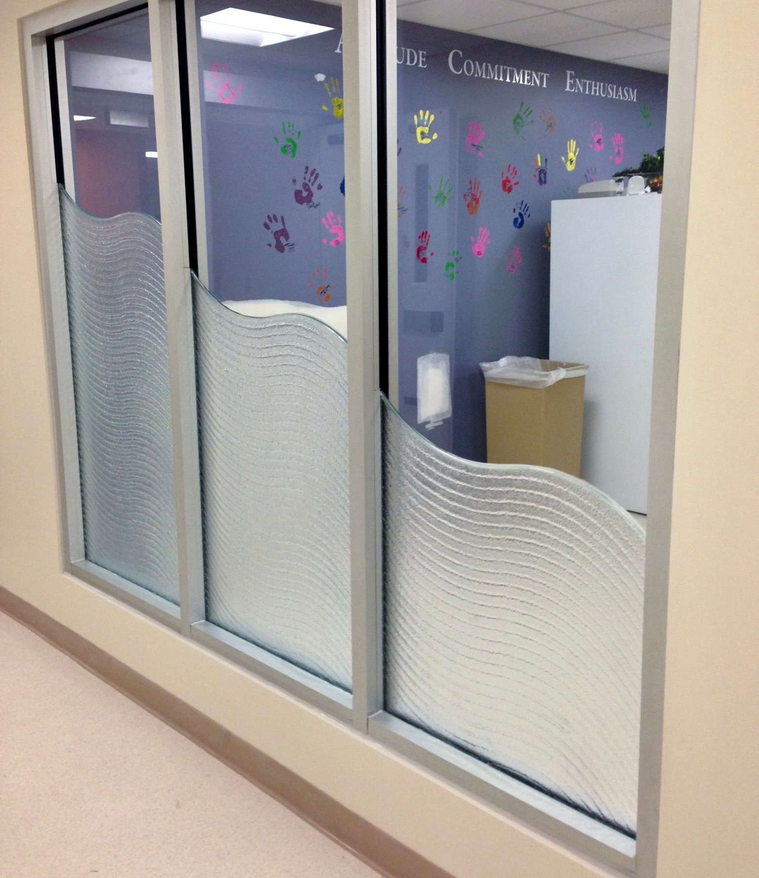 Glass doors with wave-shaped etched patterns, leading into a room with paw prints on the wall.