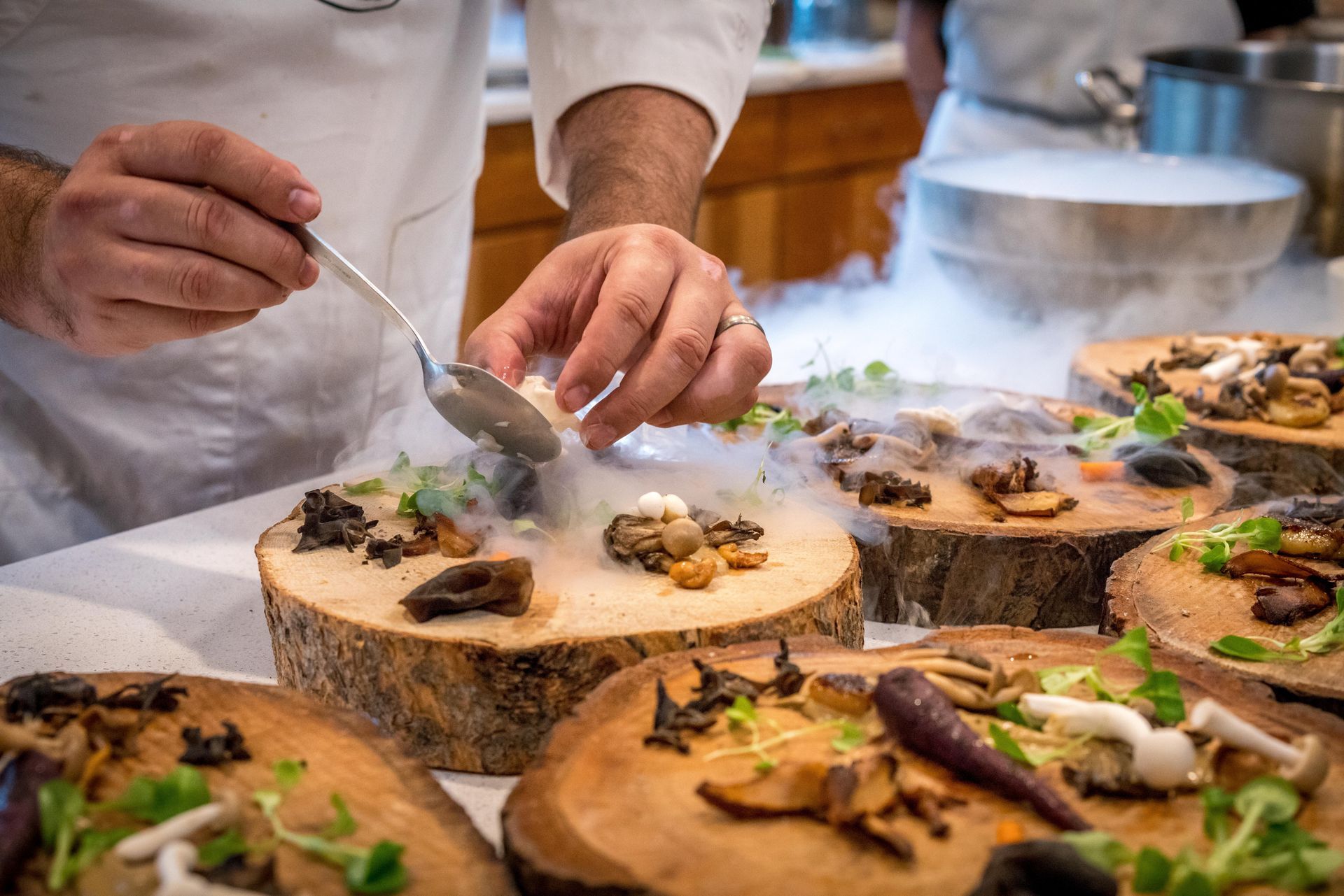 A chef plating oysters onto wooden rounds as serving platters A chef plating oysters onto wooden rounds as serving platters