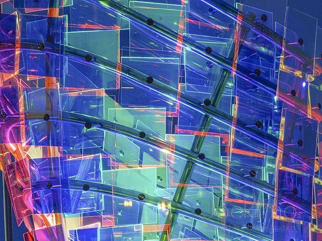 Abstract geometric pattern with layered blue, purple, and green translucent shapes and orange accents
