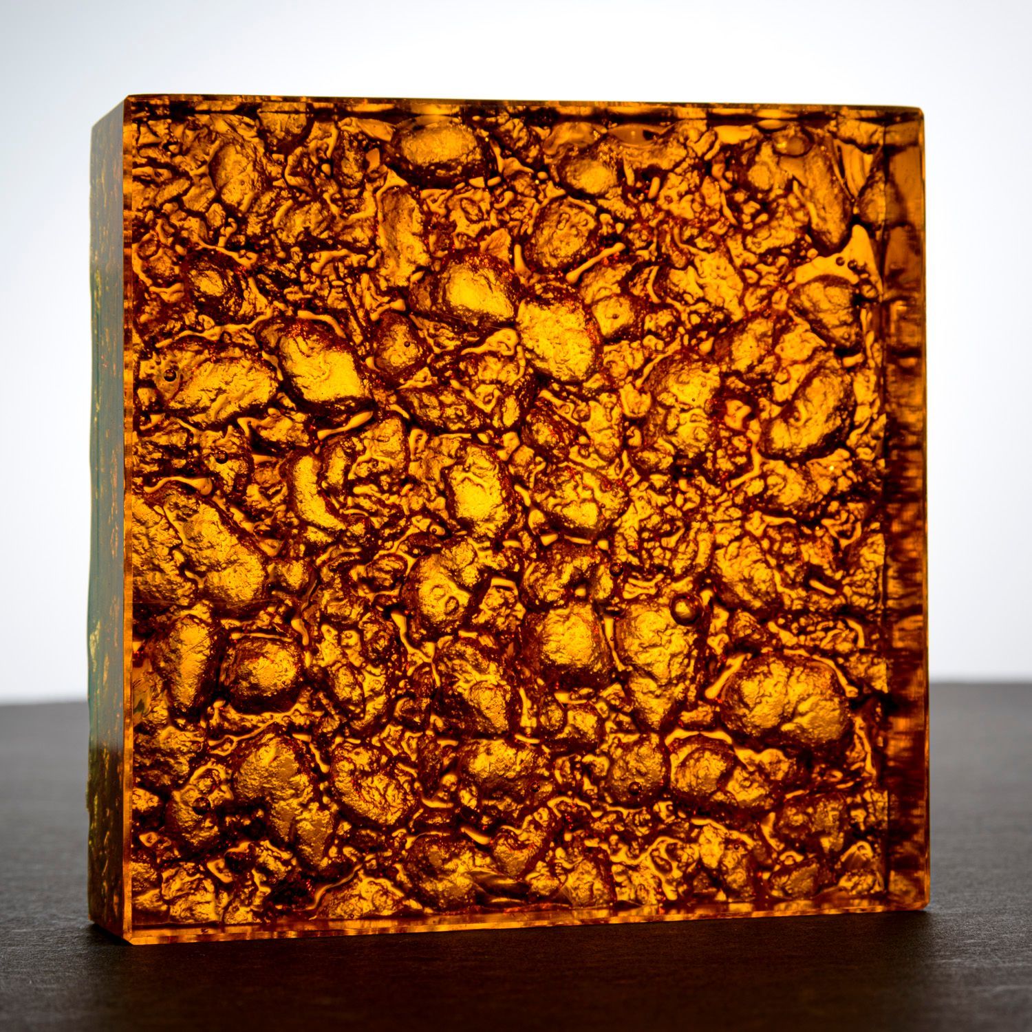 A square piece of amber glass counter top brown texture is sitting on a table.